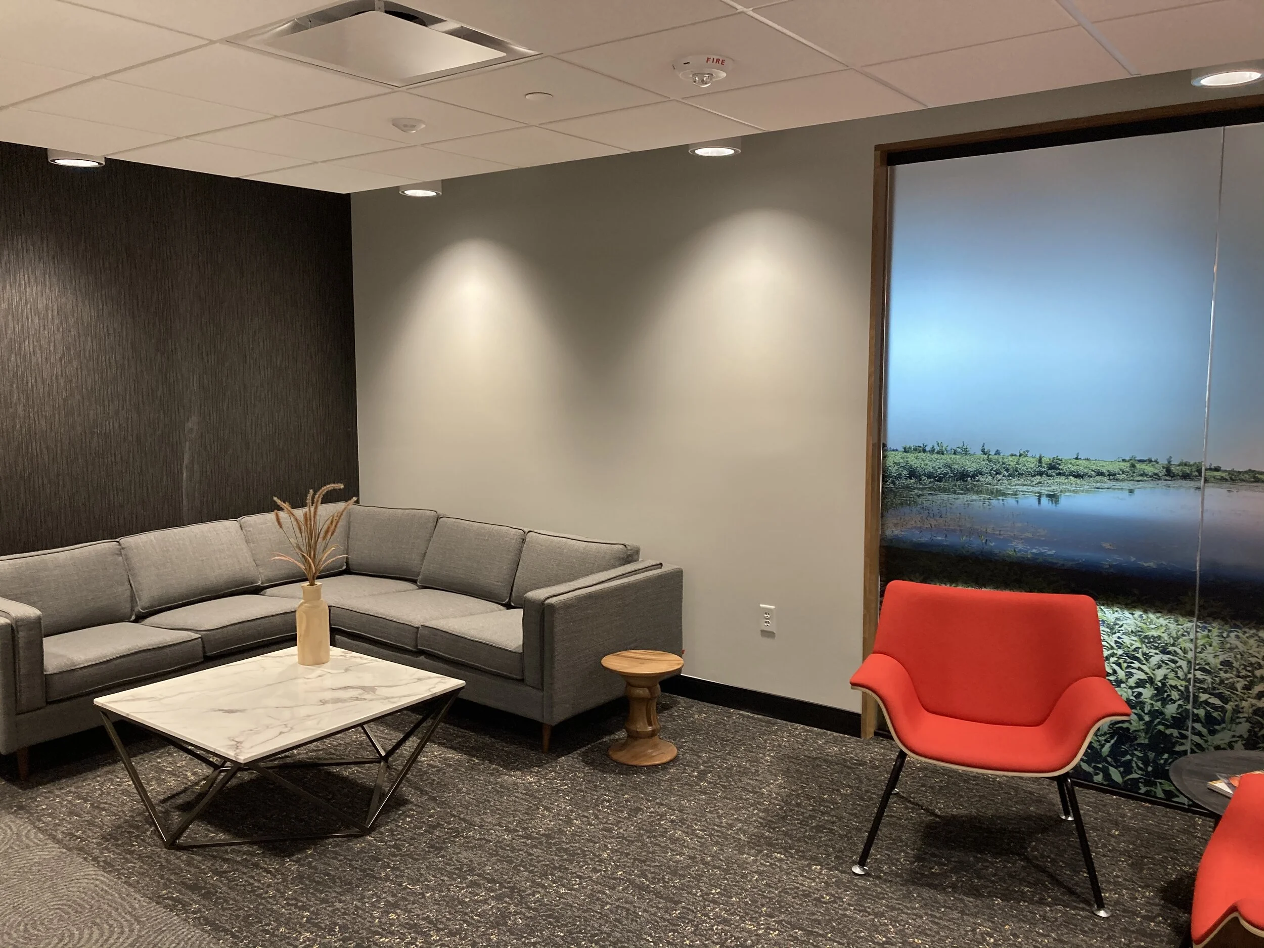 Lounge with a gray sectional, red armchair and a large landscape photo mural