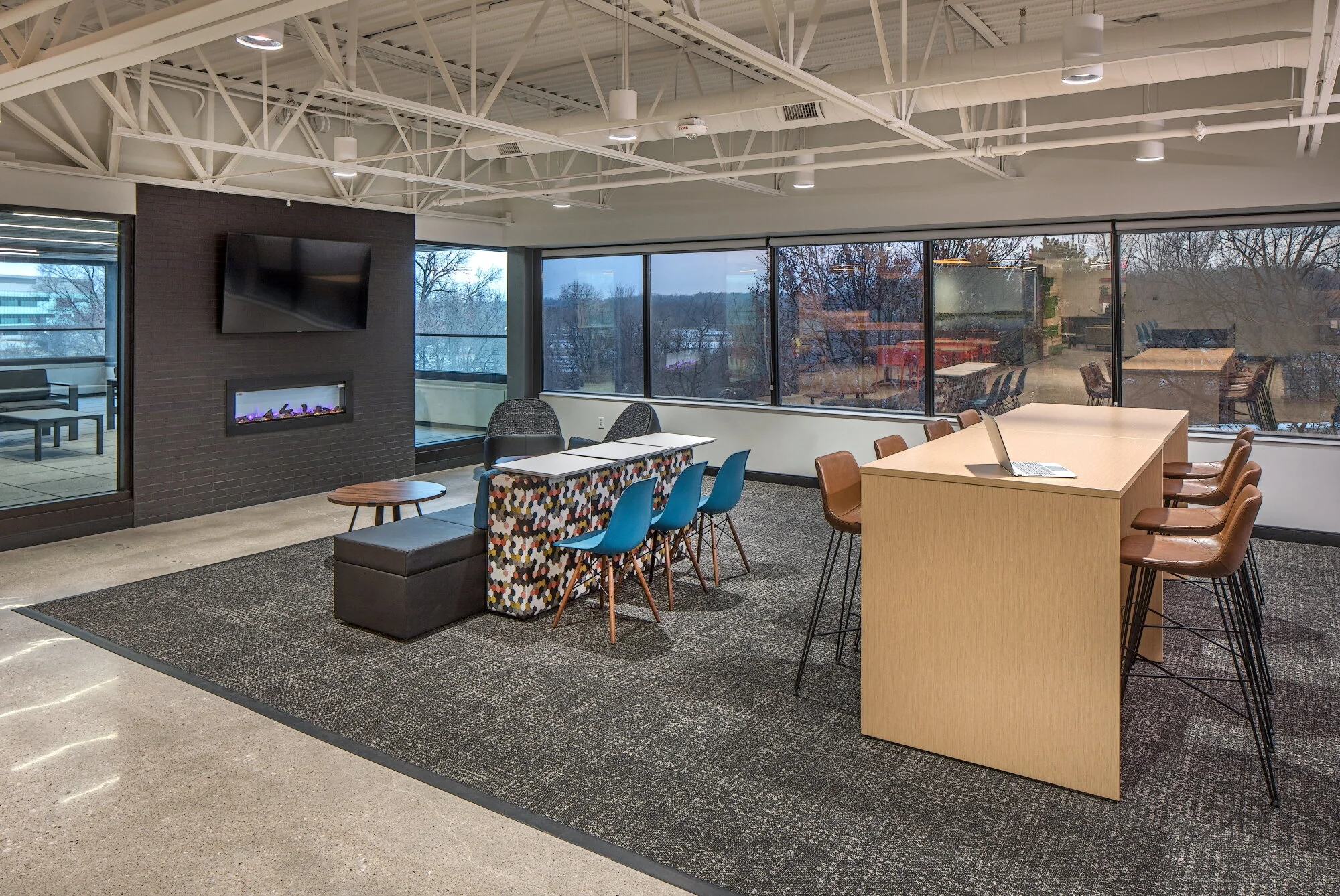 Cafe area with a wood high-top table, bar stools and a fireplace under a TV