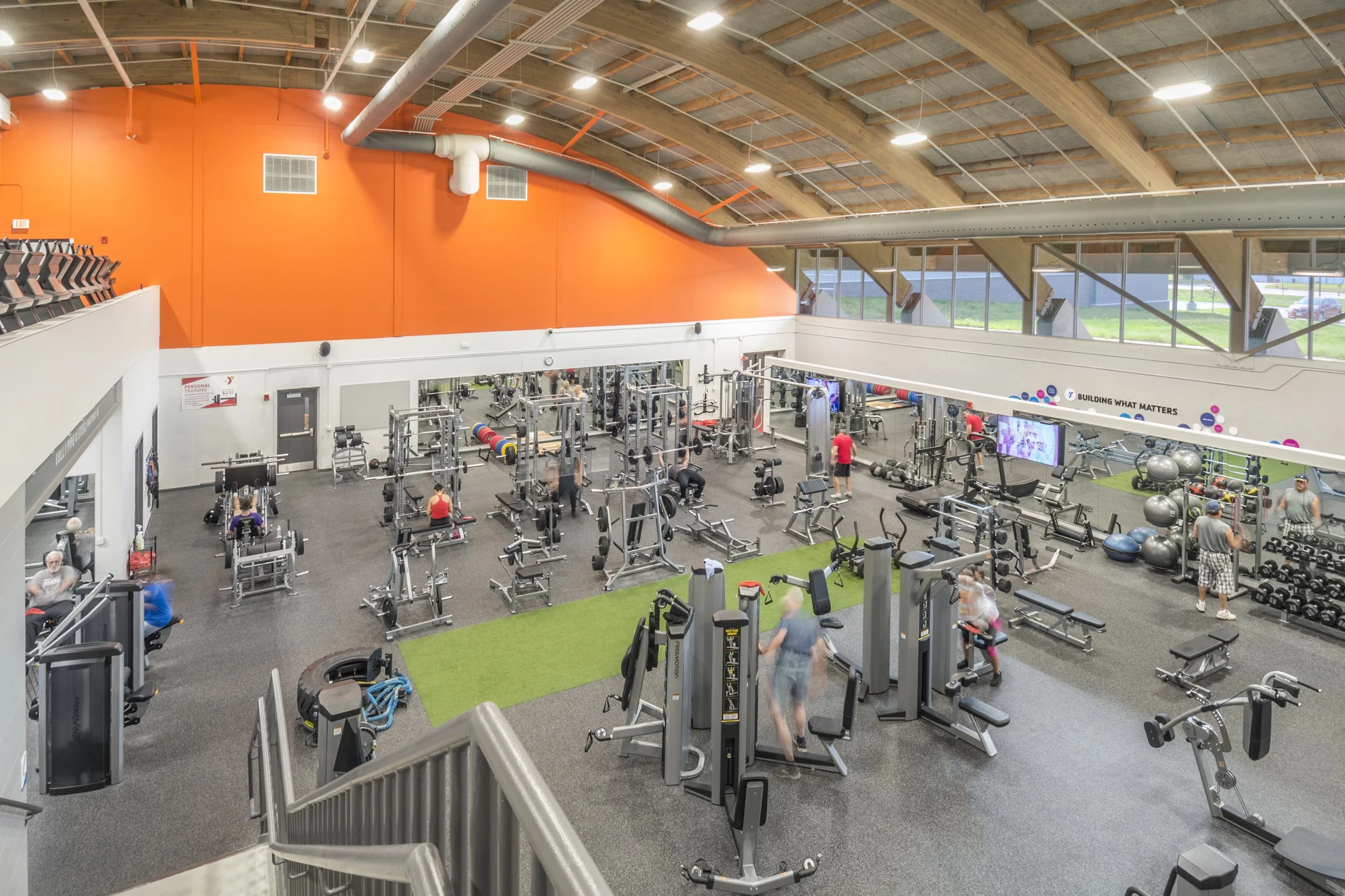 Fitness floor with strength equipment, turf strip and orange accent wall
