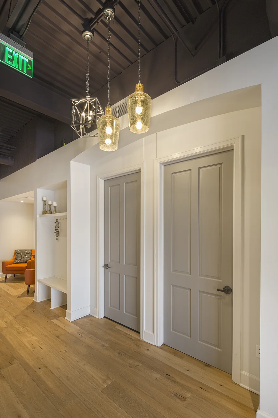 Hallway with white doors, brass pendant lights and wood floors