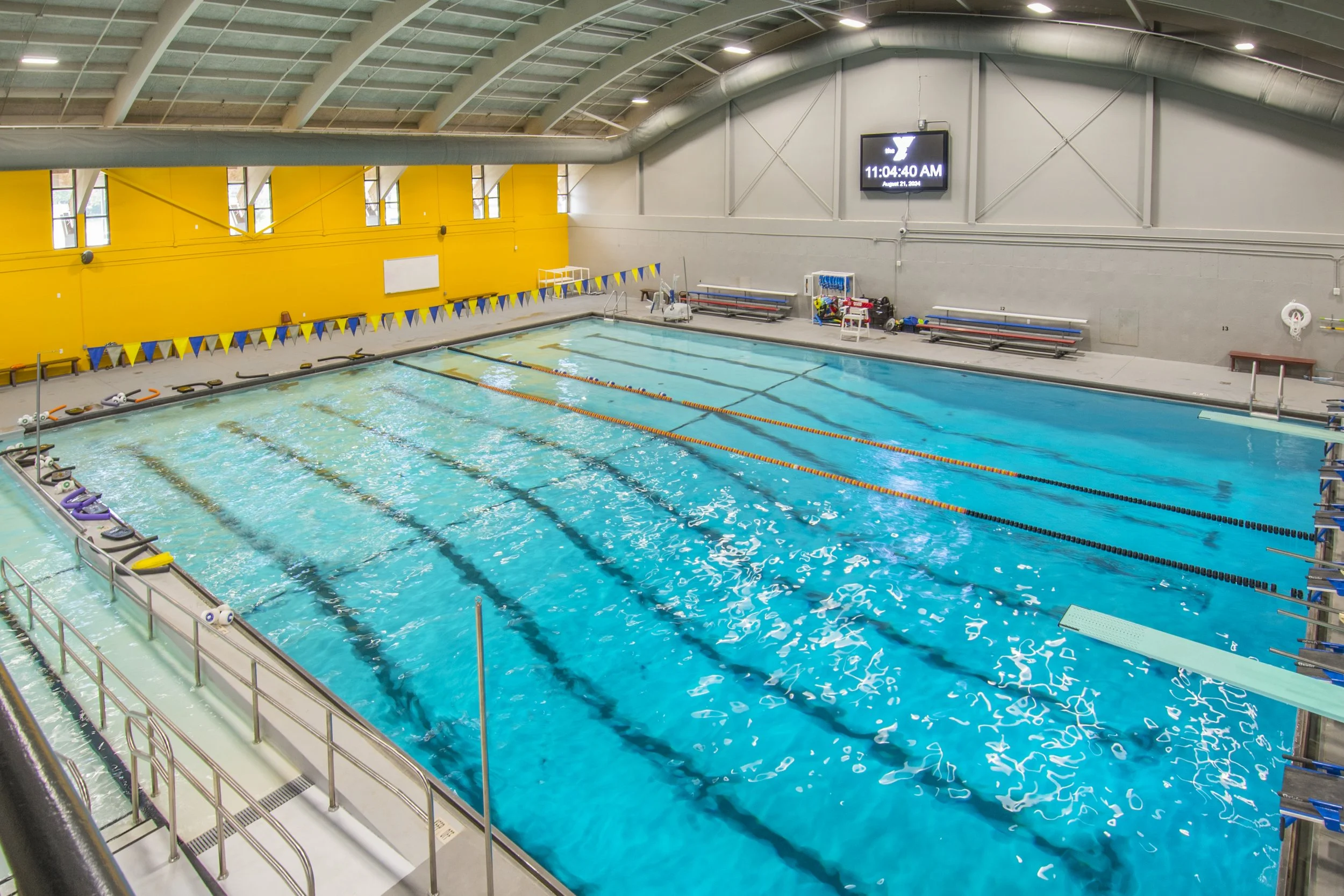 Six-lane indoor pool with orange accent wall and lane lines