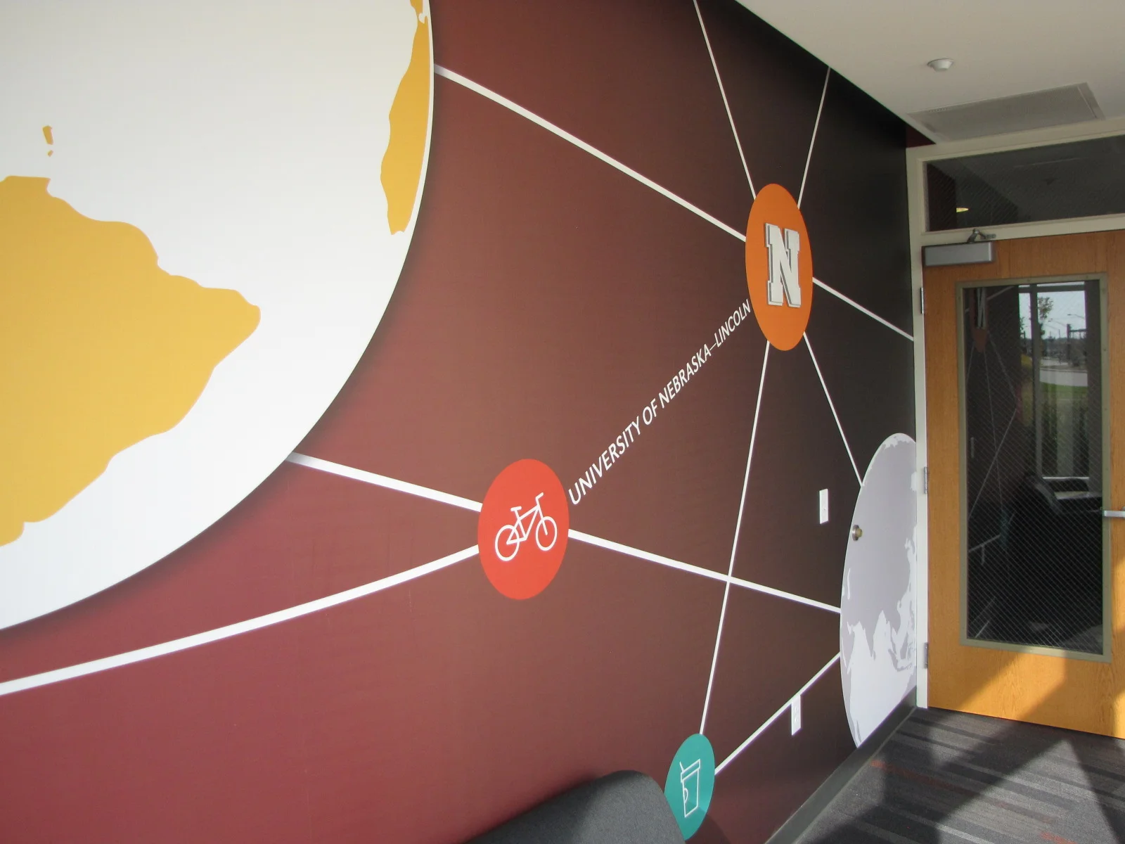 Lobby wall mural of a world map with Nebraska icons and connecting lines