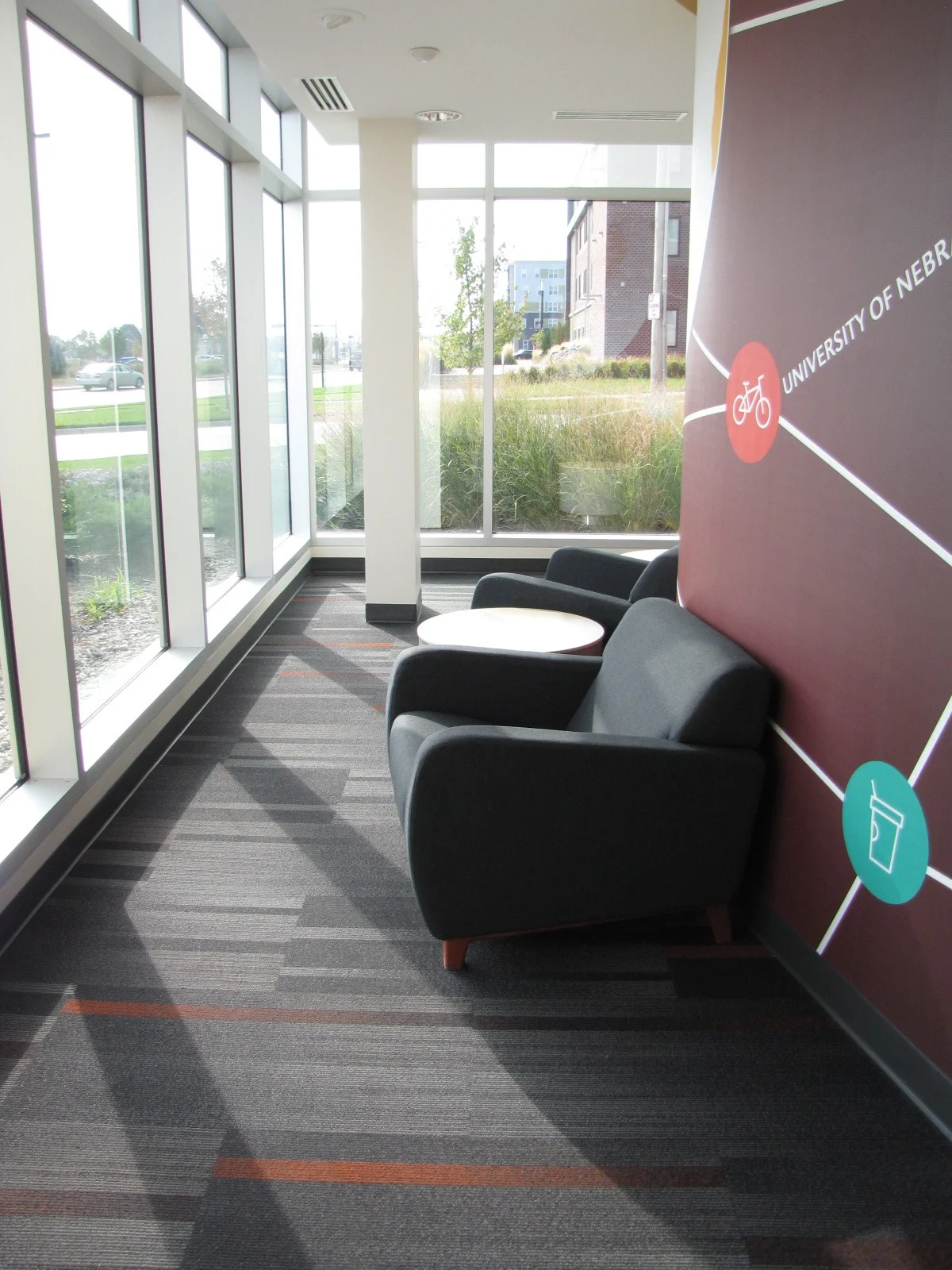 Lounge seating by floor-to-ceiling windows with striped carpet
