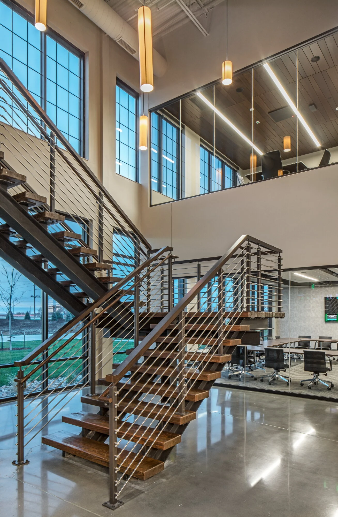 Open stair with wood treads and cable railing in a two-story lobby