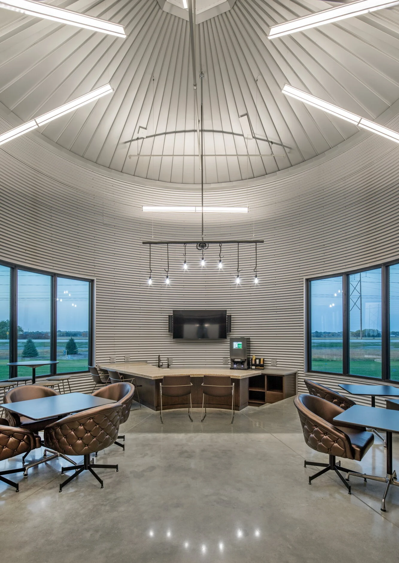 Round conference room with a curved wood slat ceiling and a live-edge table
