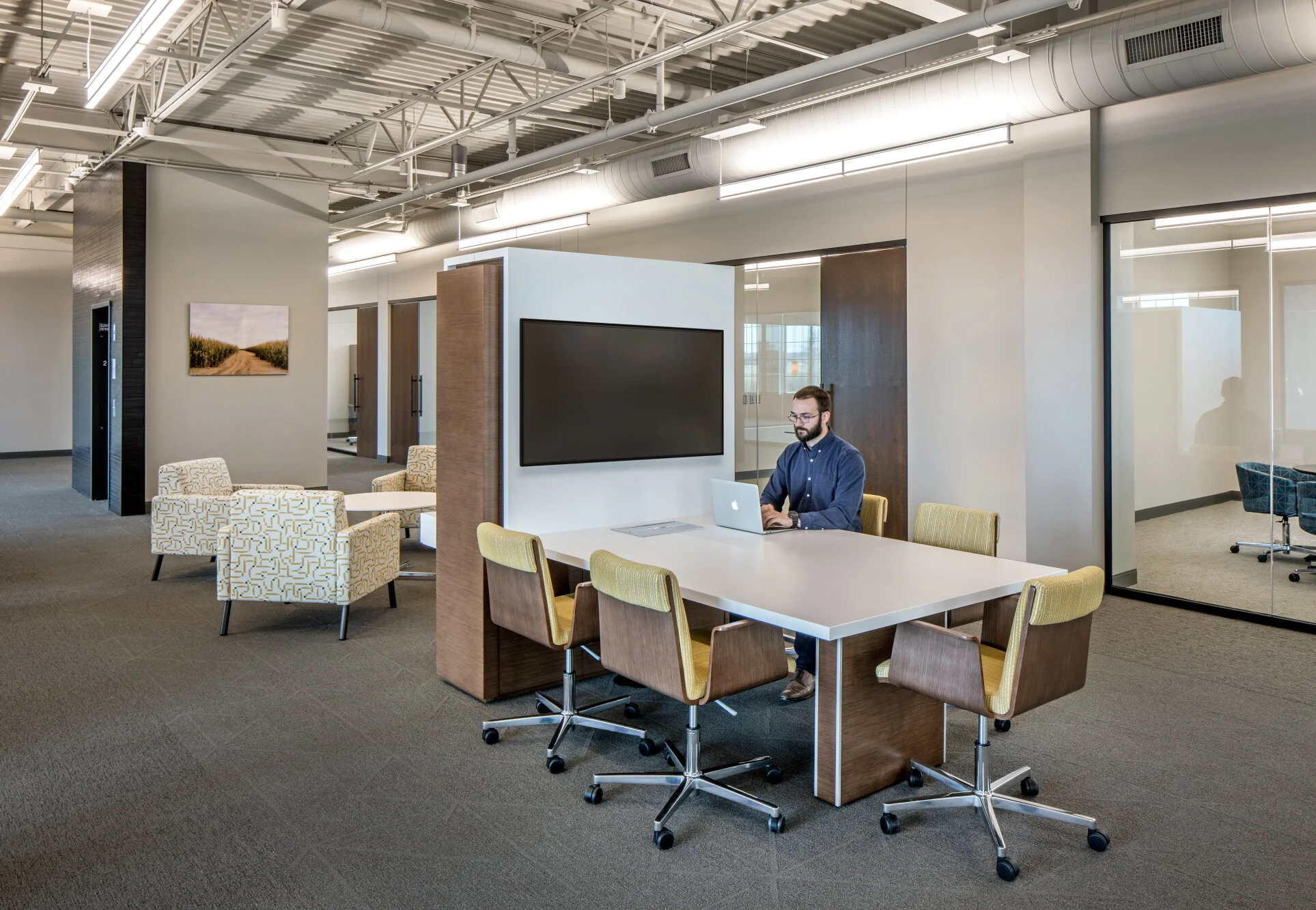 Meeting room with a wood-framed media wall, white table and green chairs