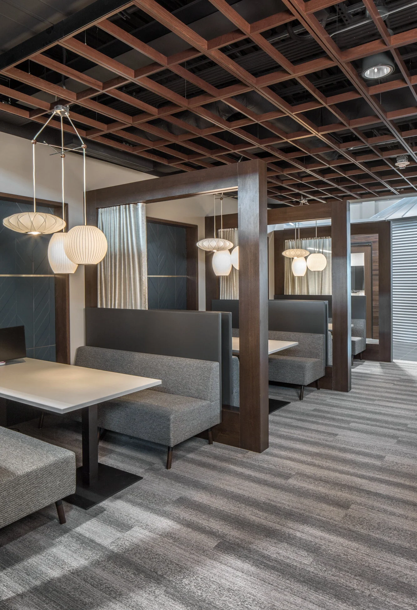 Booth seating under exposed wood trusses and pendant lights