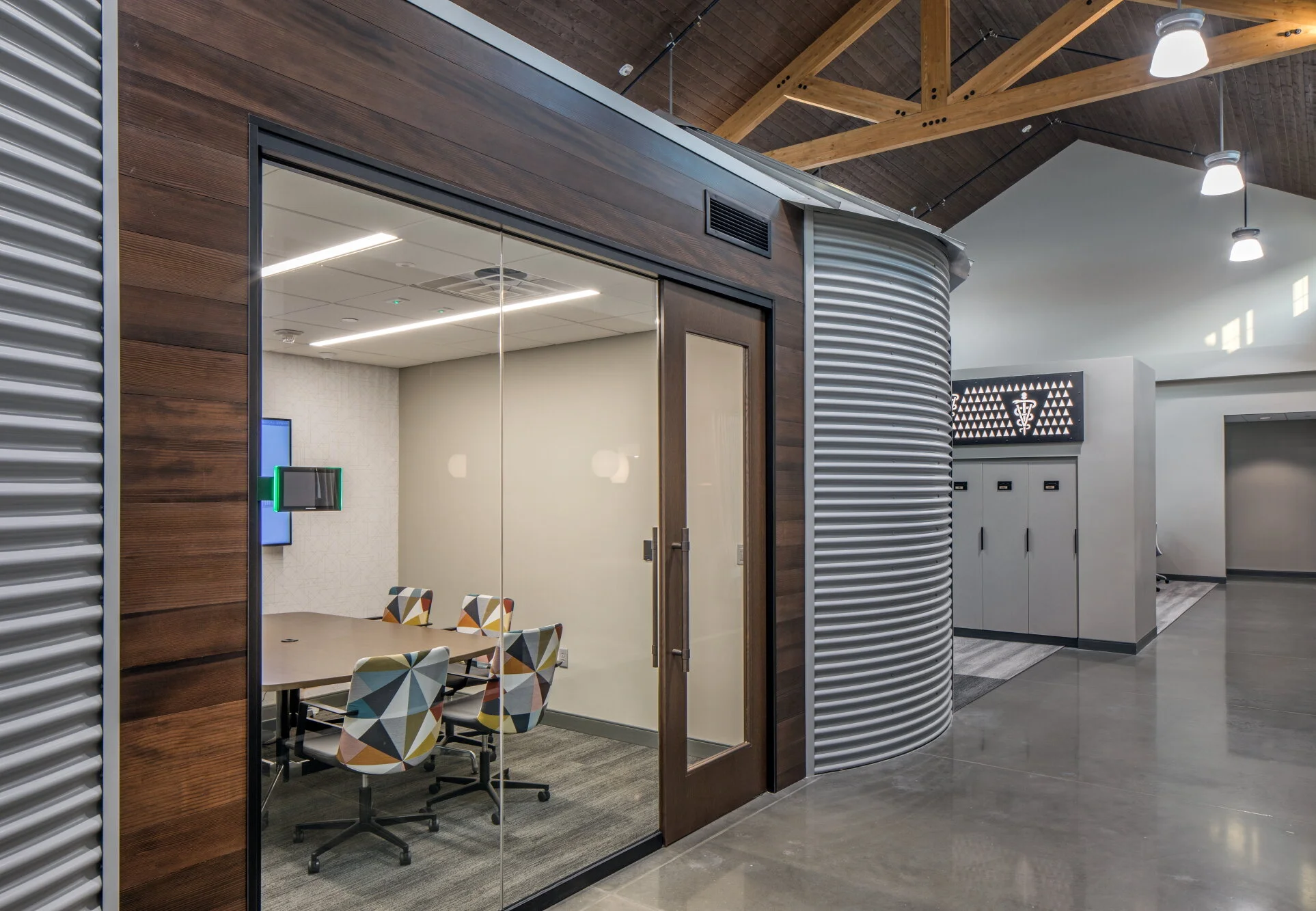 Conference room wrapped in corrugated metal and wood with timber trusses overhead
