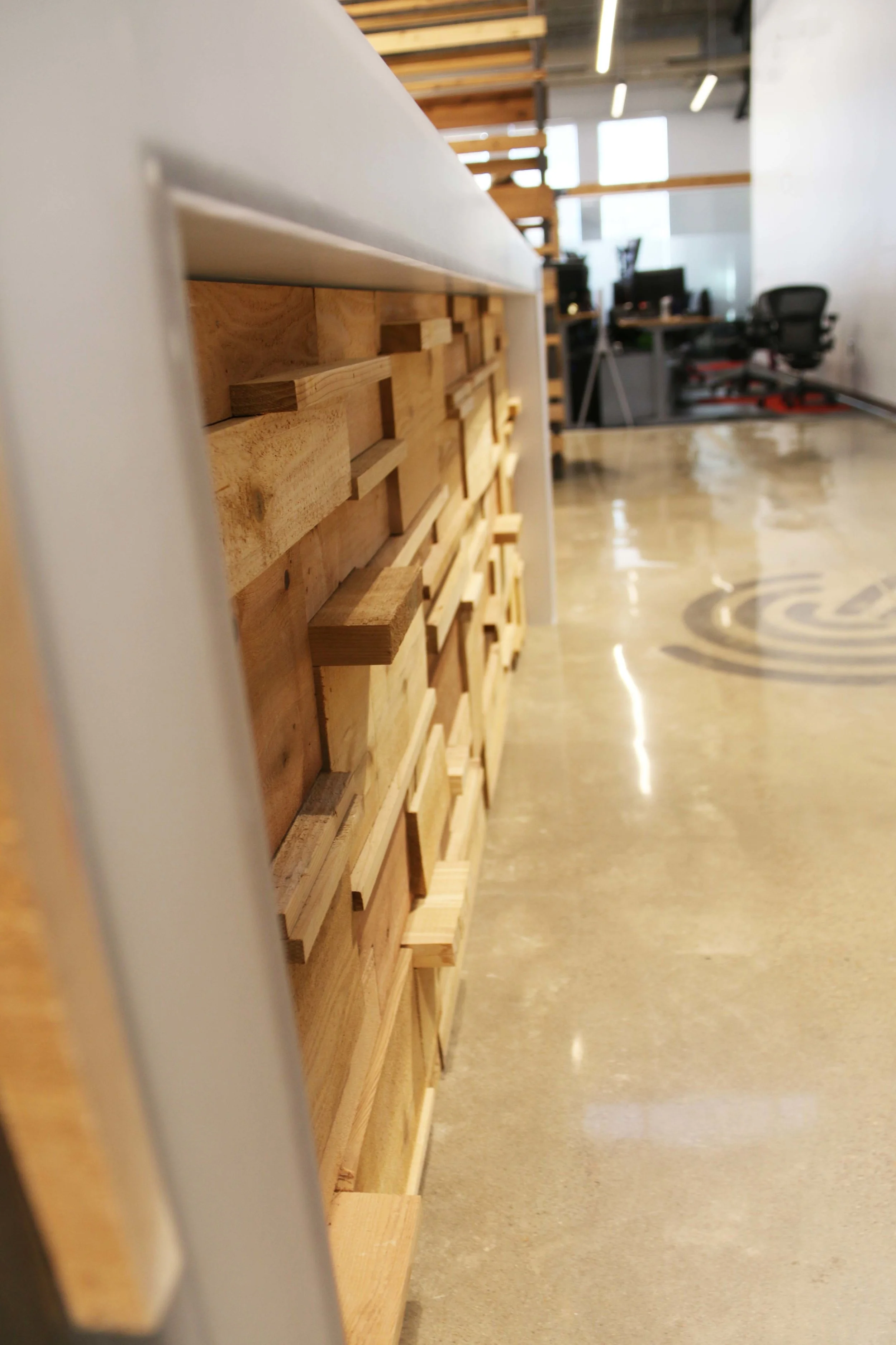 Stacked reclaimed wood wall detail along an office corridor