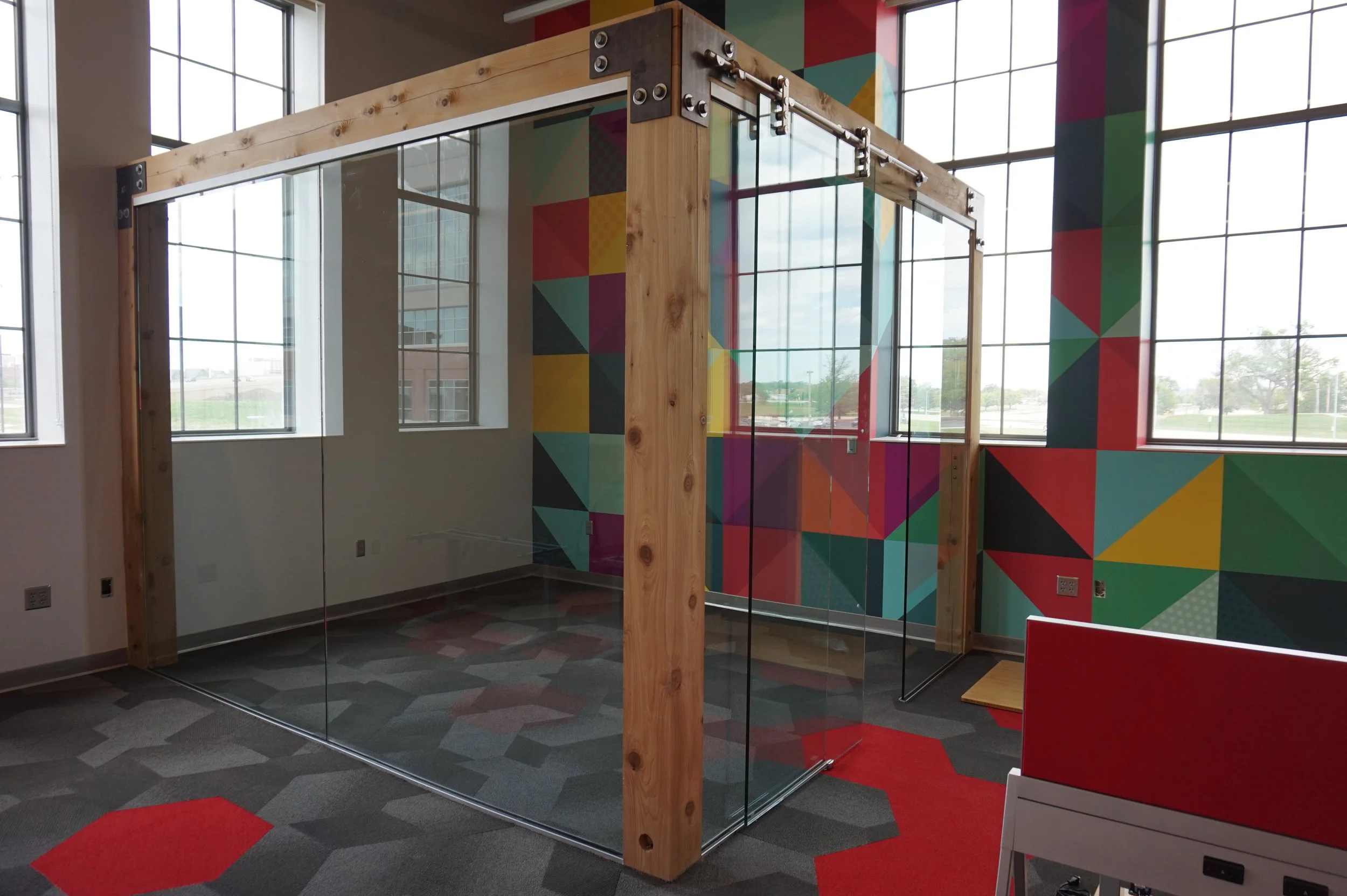 Timber-framed meeting space with a multicolored geometric wall graphic