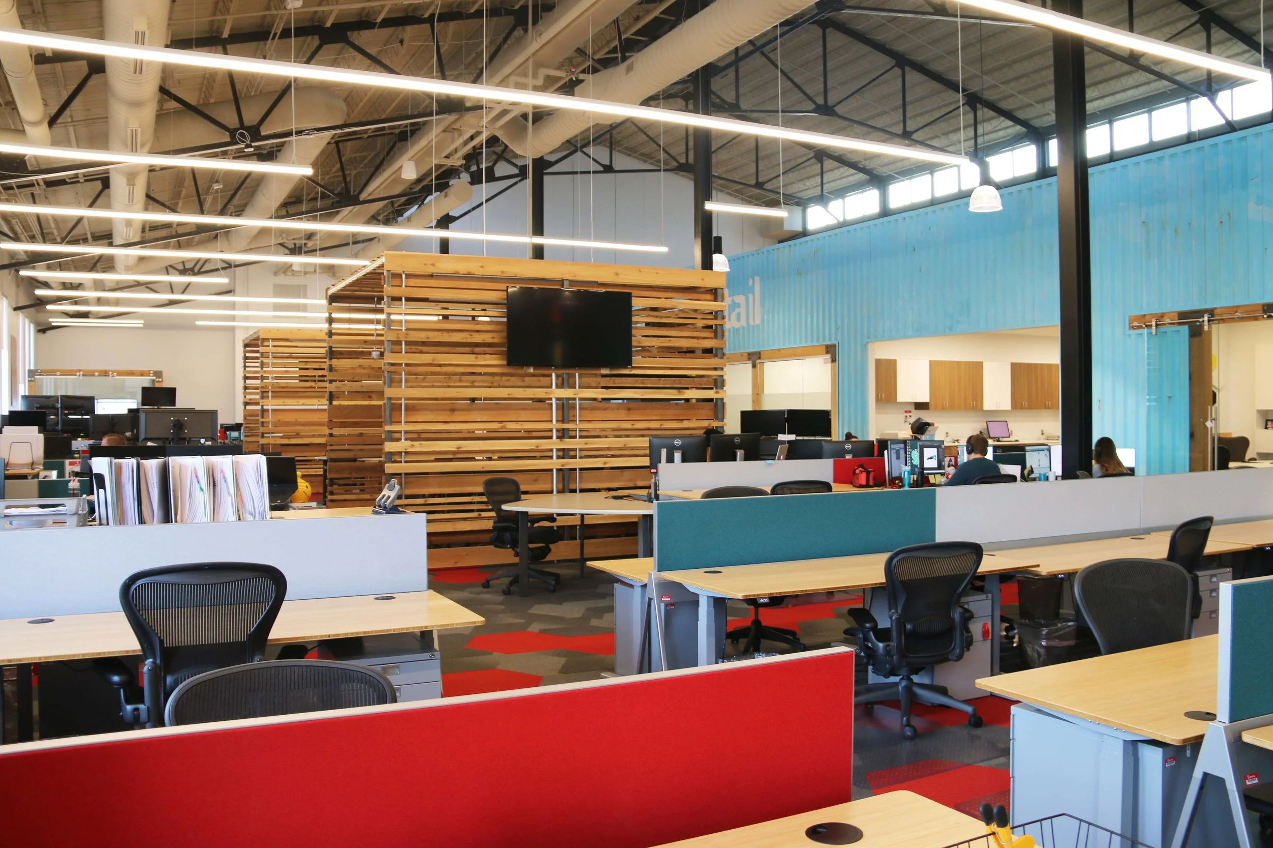 Open office with sit-stand desks, red panels and reclaimed wood accents