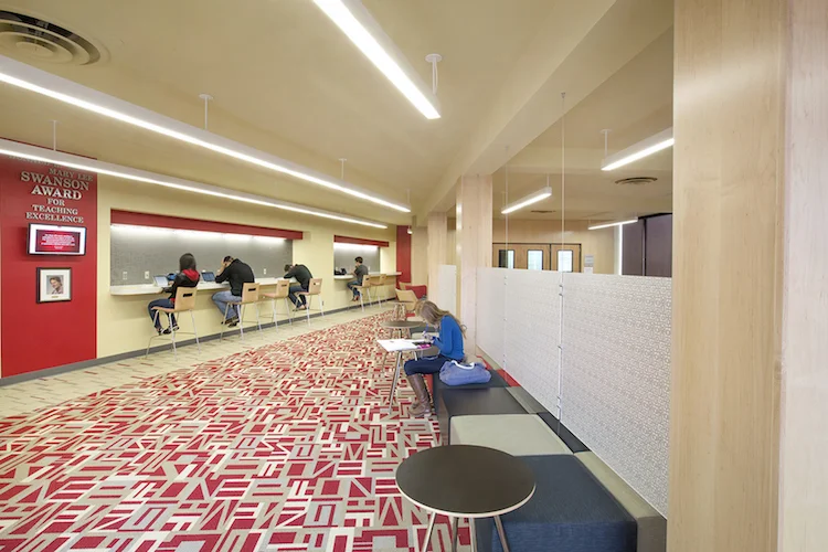 Student lounge in Henzlik Hall at UNL with red patterned carpet, wood columns and a red accent wall