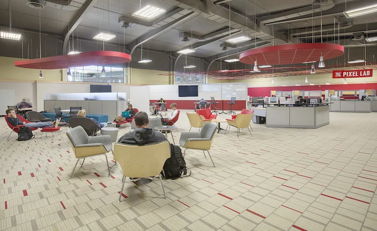 Open lounge with red acoustic ceiling clouds, gray armchairs and carpet tile