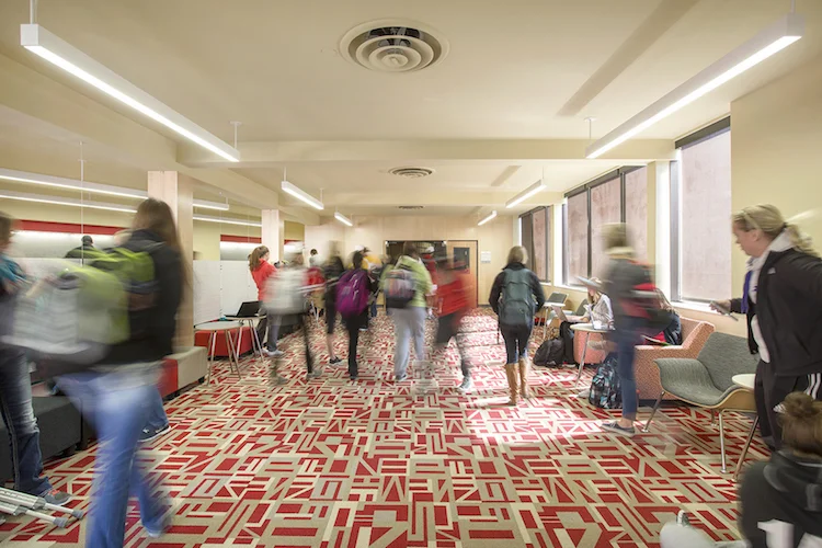 Students walking through the Henzlik Hall corridor with red patterned carpet