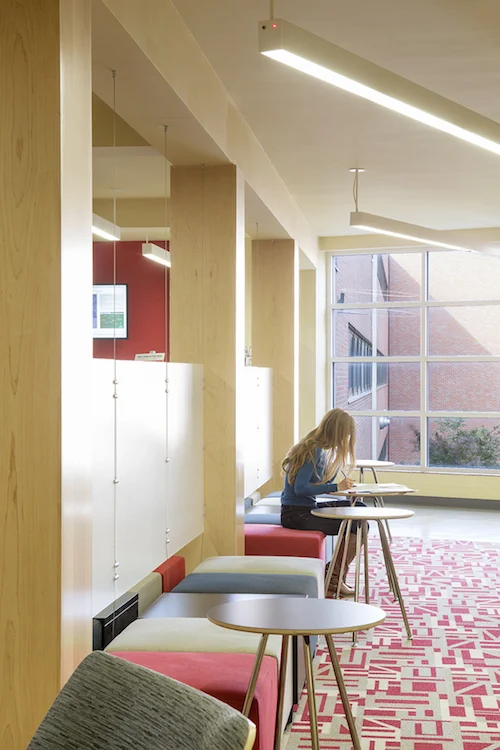Student study area with high-top seating, wood screens and red carpet