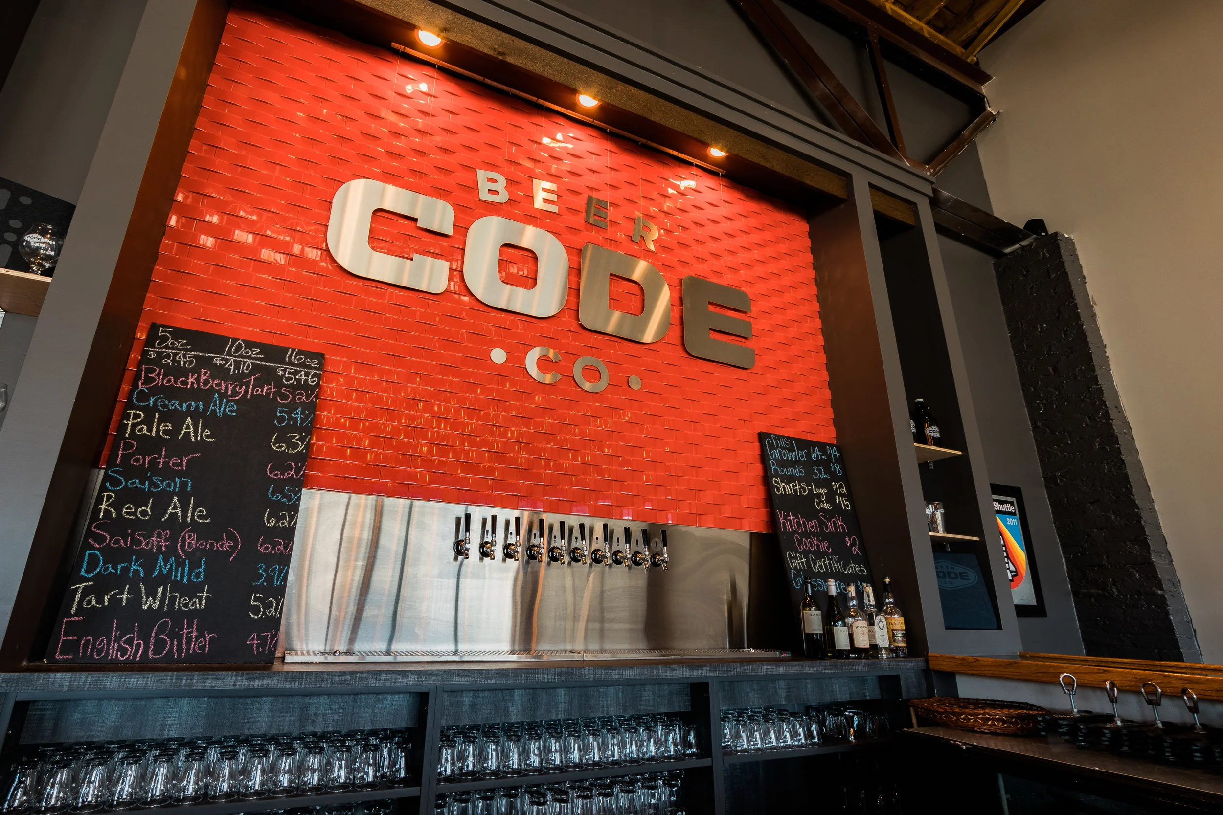 Orange Code Beer Co. logo wall behind the bar with a chalkboard tap list
