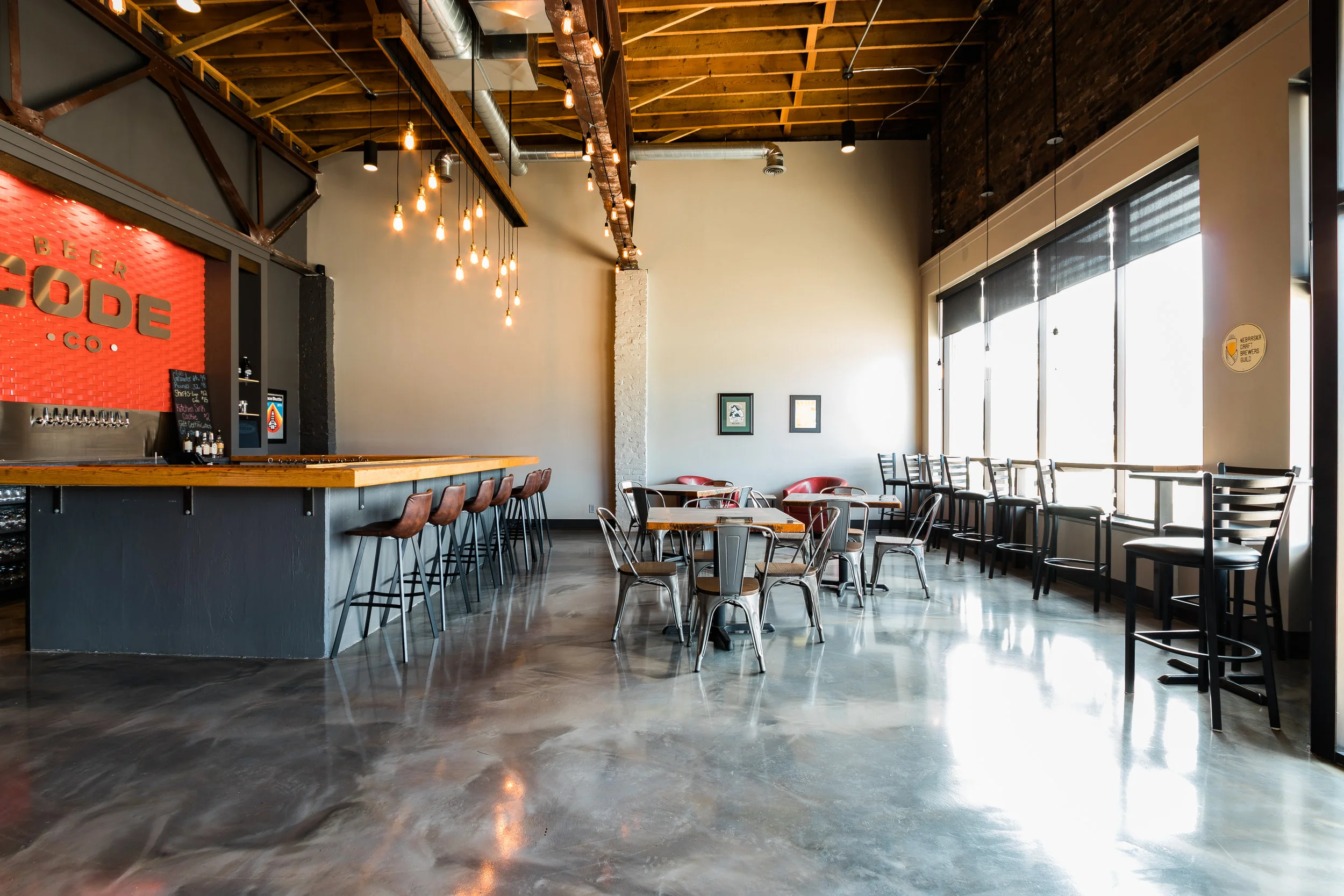 Bar with a wood top, stools and the Code Beer Co. logo wall