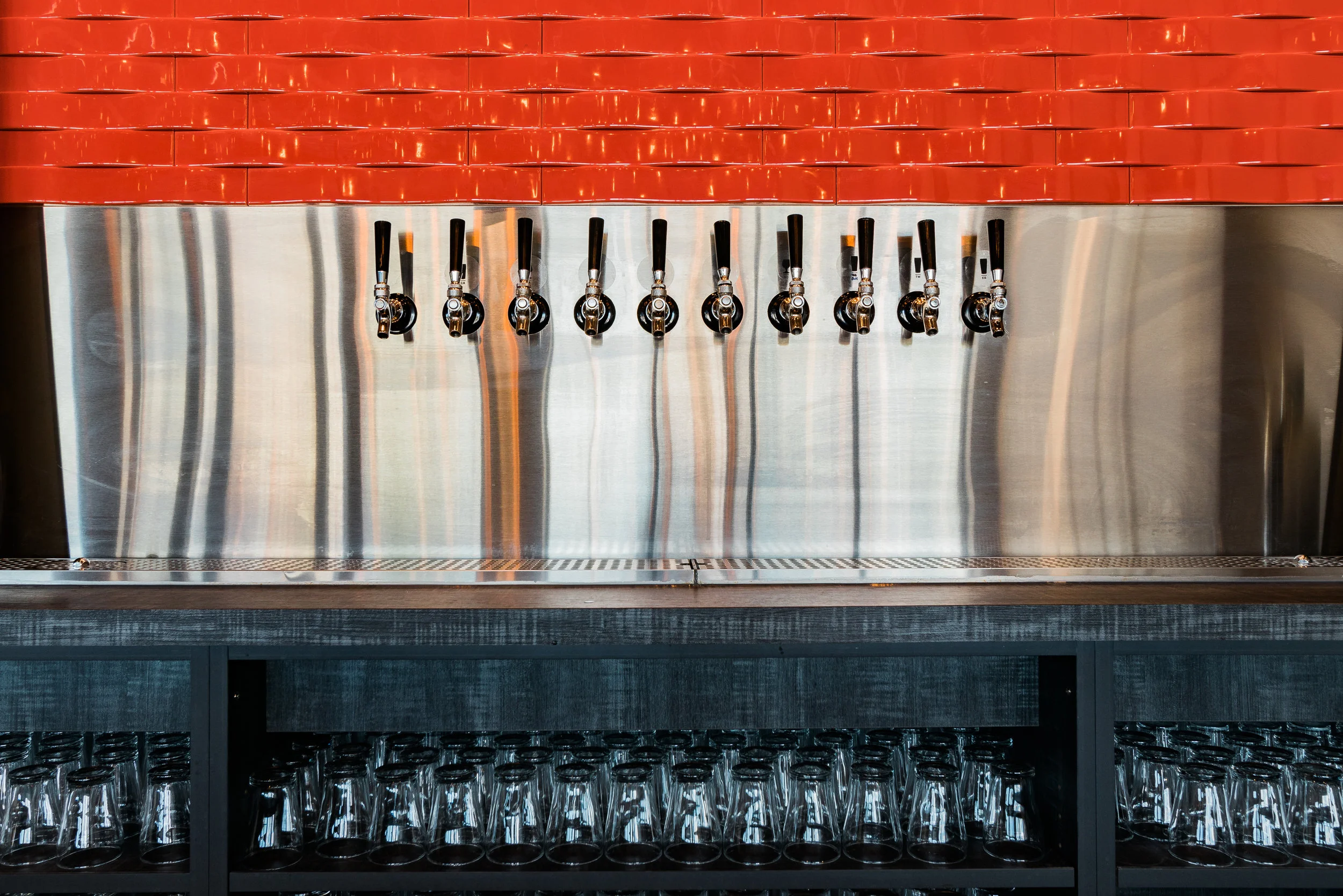 Row of stainless beer taps against an orange brick wall