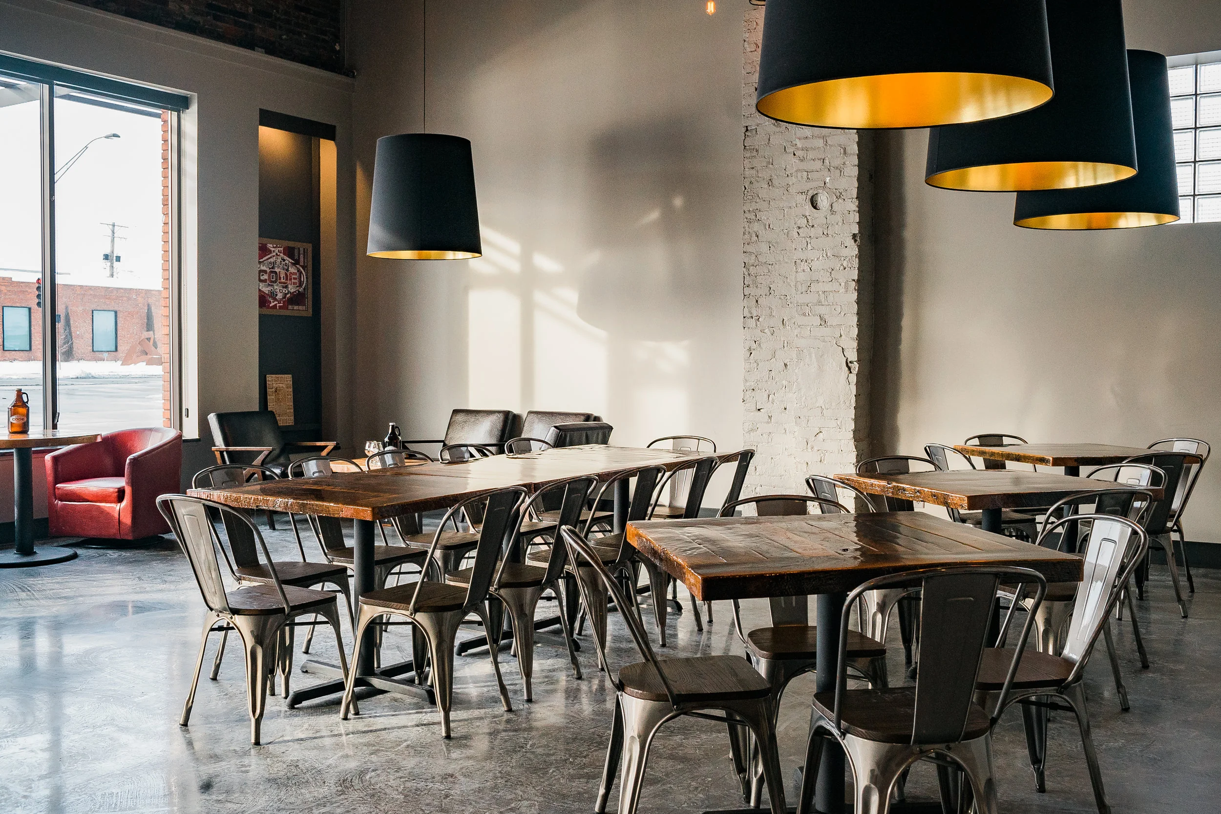 Taproom seating with concrete floors, black pendant lights and framed art