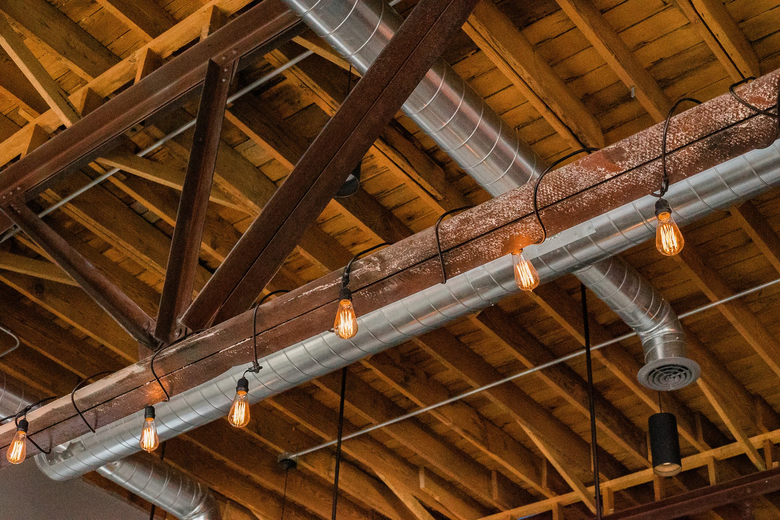 Exposed timber trusses and ductwork in the brewery ceiling