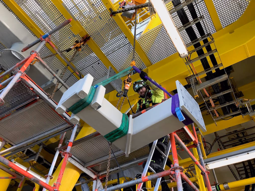 Monteur von mh² offshore hebt einen Stahlträger unter einer Offshore-Plattform ein