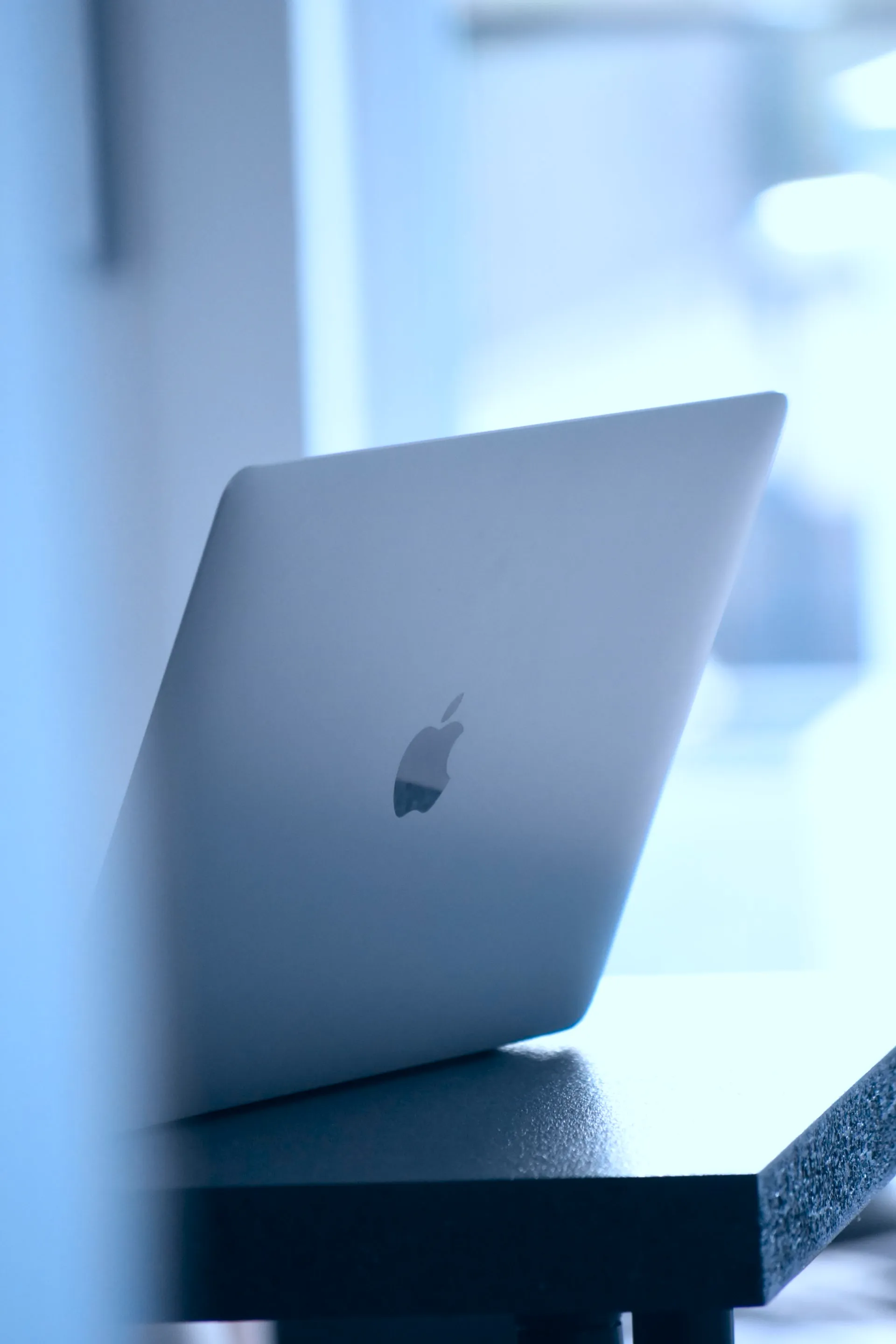 Zijaanzicht van een zilveren MacBook op bureau ter illustratie van veelgestelde vragen over ons Webflow agency