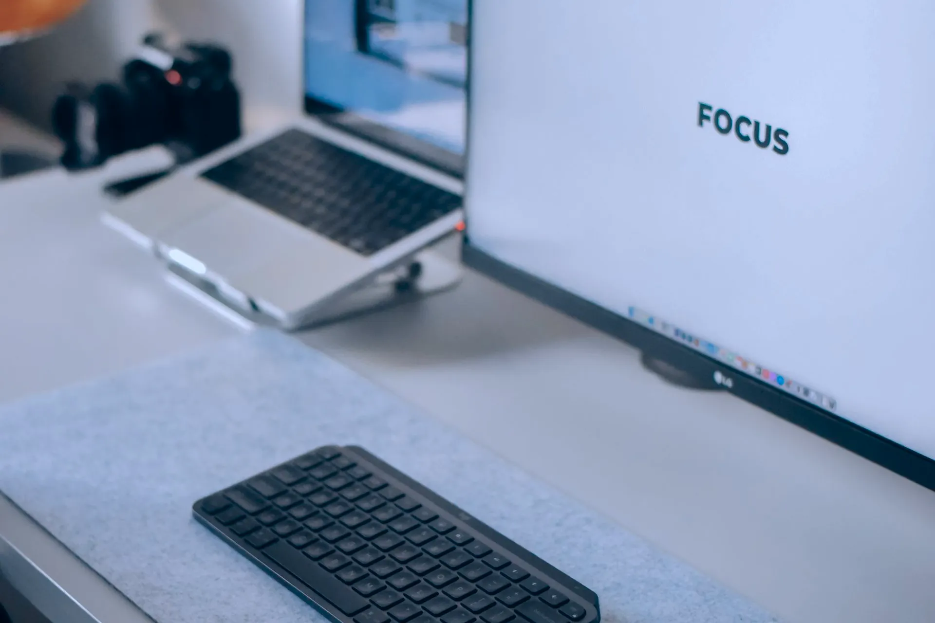 Moderne werkplek met een laptop, extern beeldscherm met de tekst FOCUS en een draadloos toetsenbord voor webdesign en development bij Netflow Agency.