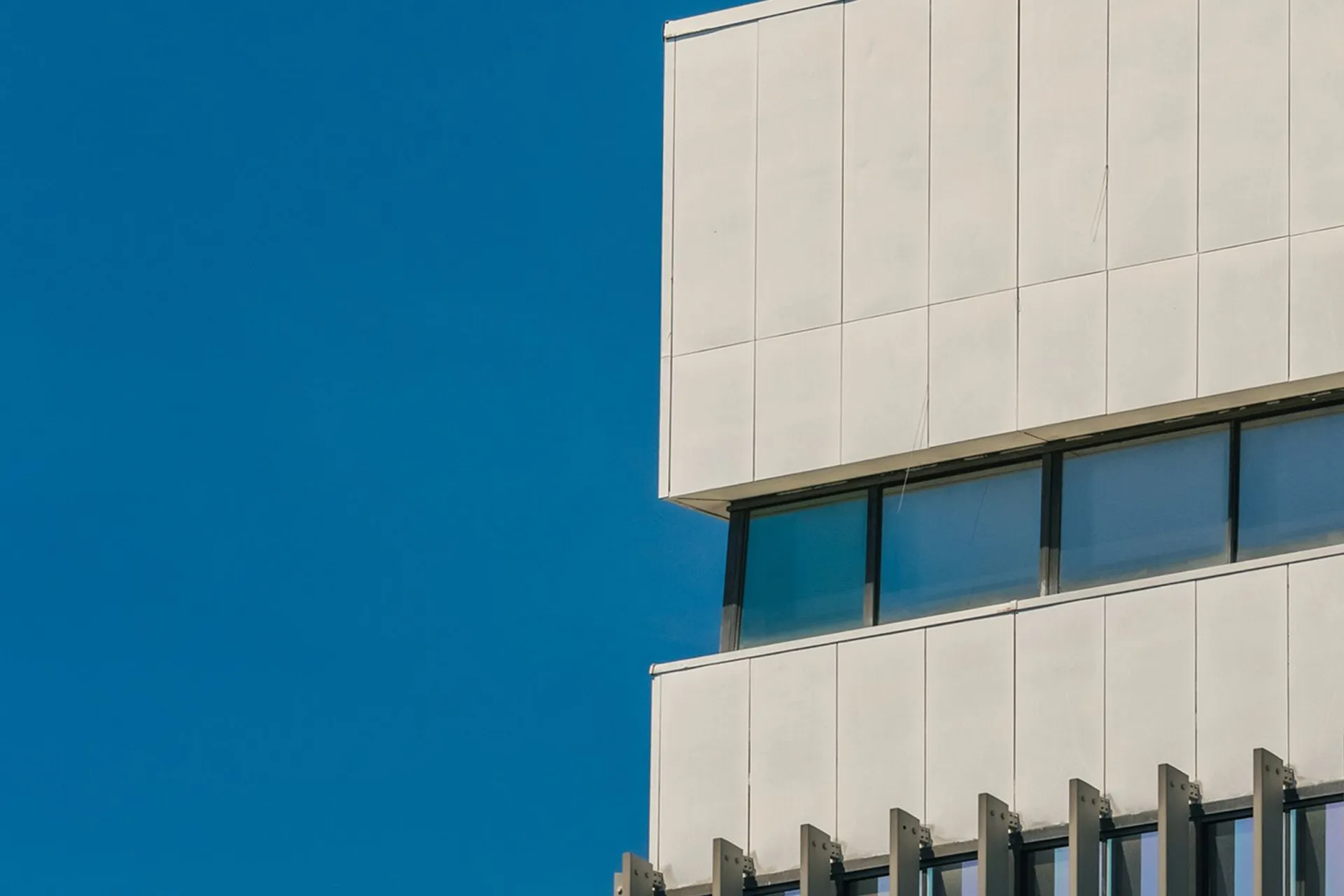 Minimalistische architectuur van een modern kantoorpand met strakke lijnen en glas tegen een blauwe lucht voor Netflow Agency.