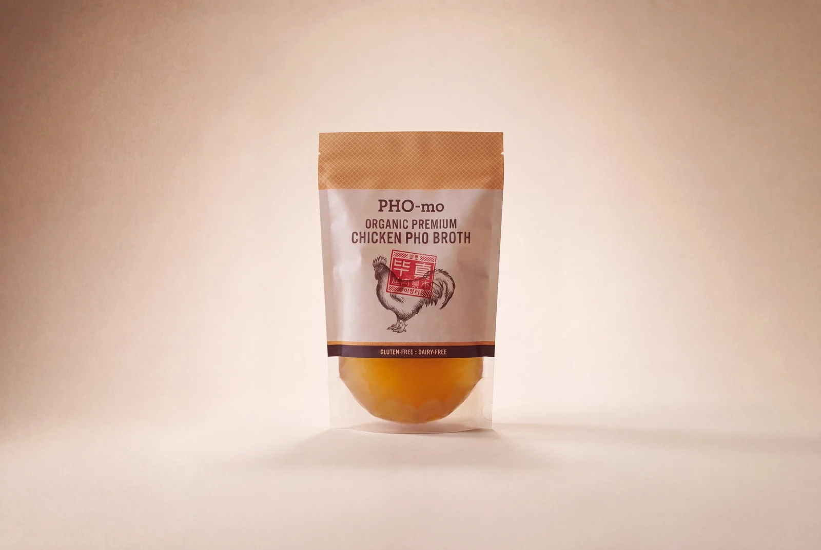 Package of PHO-mo Organic Premium Chicken Pho Broth with a rooster illustration on a beige background.