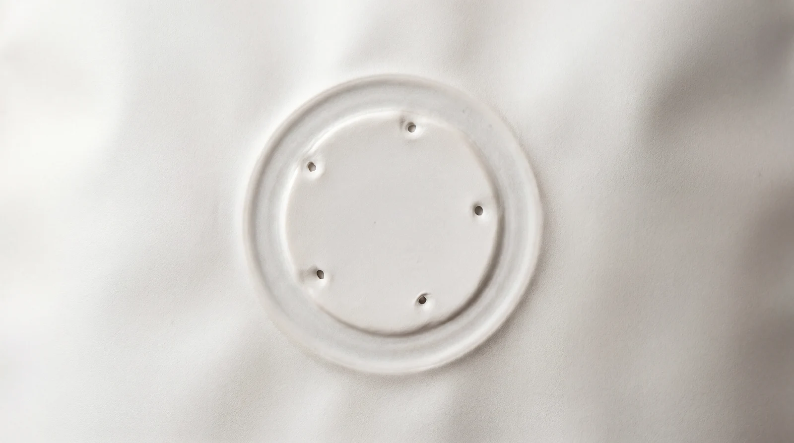 Close-up of a white round plastic valve with five small holes evenly spaced in a circle.