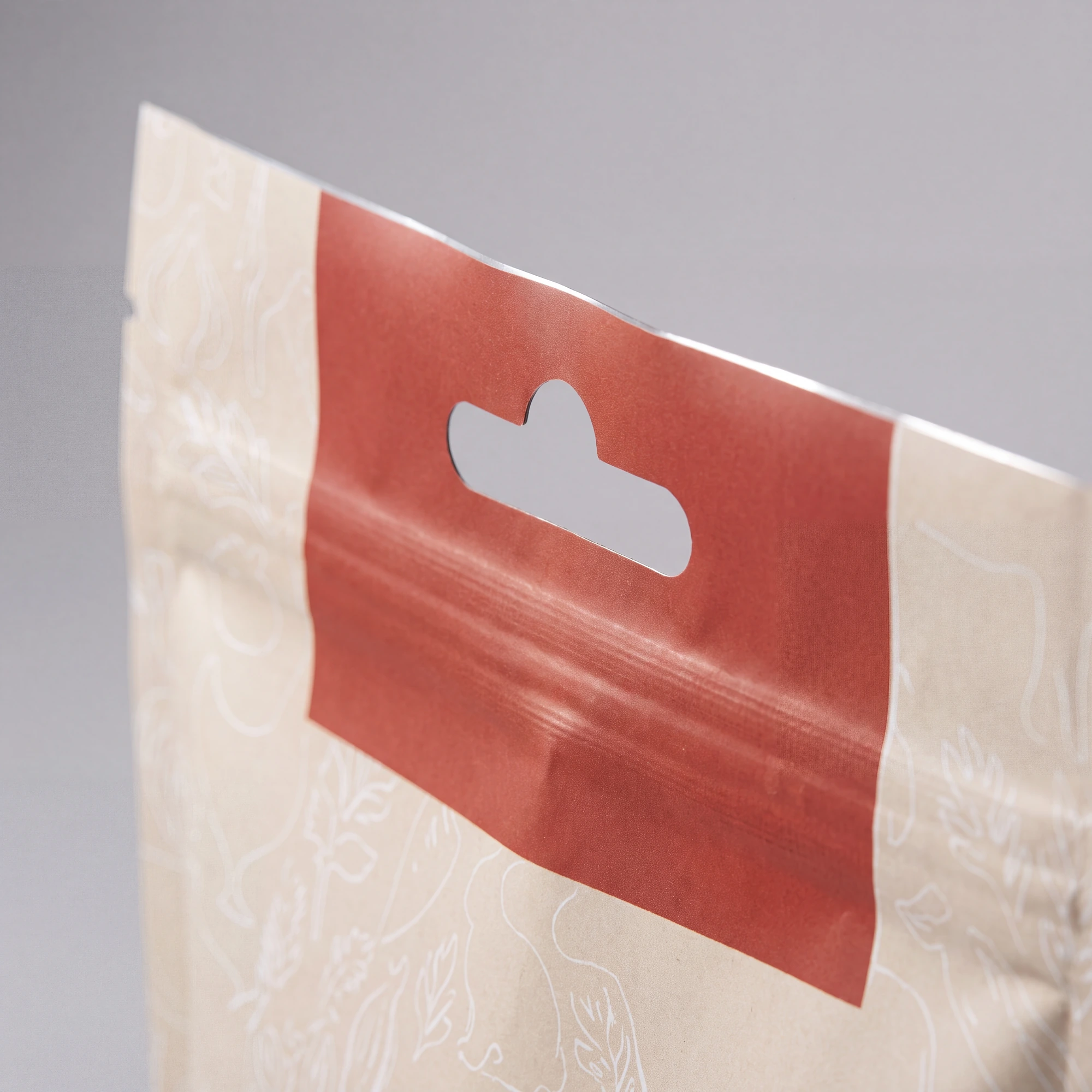 Close-up of a beige pouch with a red hang hole tab for display and hanging.
