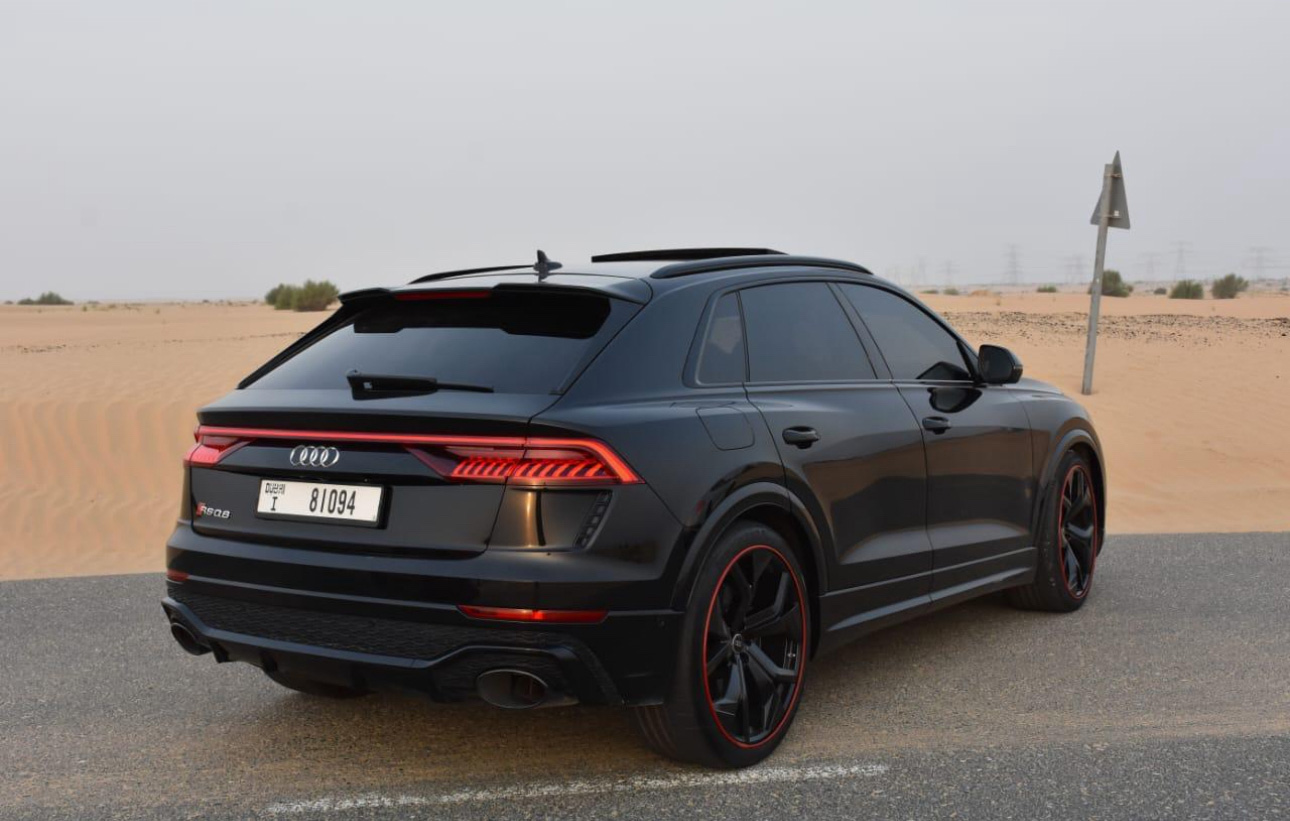 Black Audi SUV with red trim parked in desert landscape