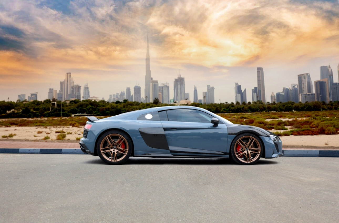 Blue sports car parked with Dubai skyline and Burj Khalifa in background