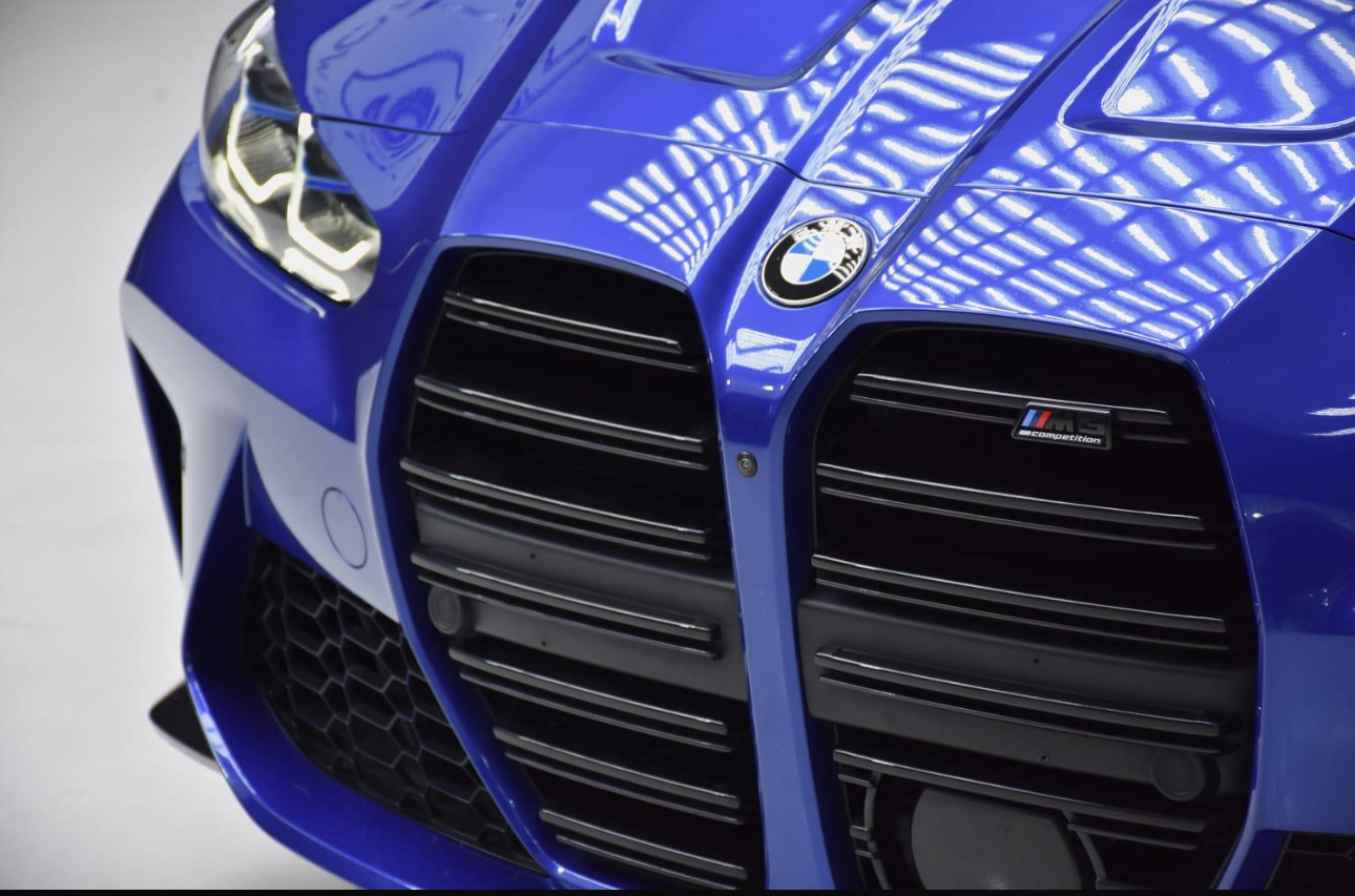 Blue BMW sports car with distinctive kidney grille and M Competition badge