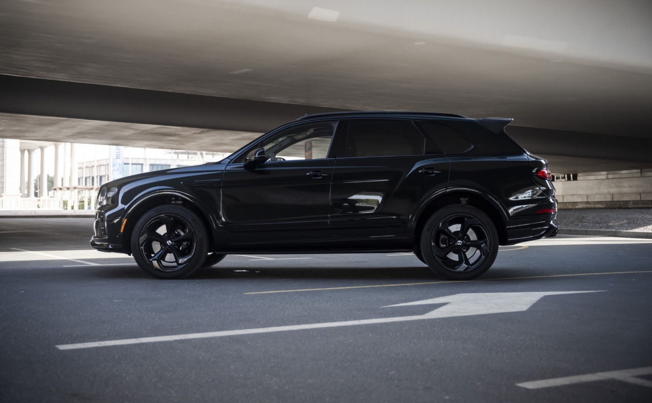 Black luxury SUV parked under concrete structure on urban street