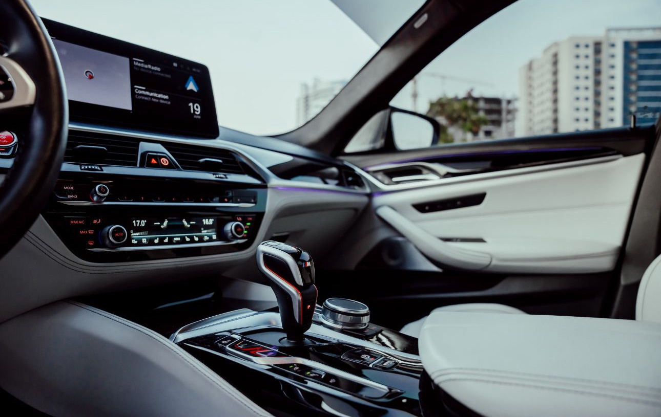 Modern car interior with digital dashboard, gear shifter, and white leather seats
