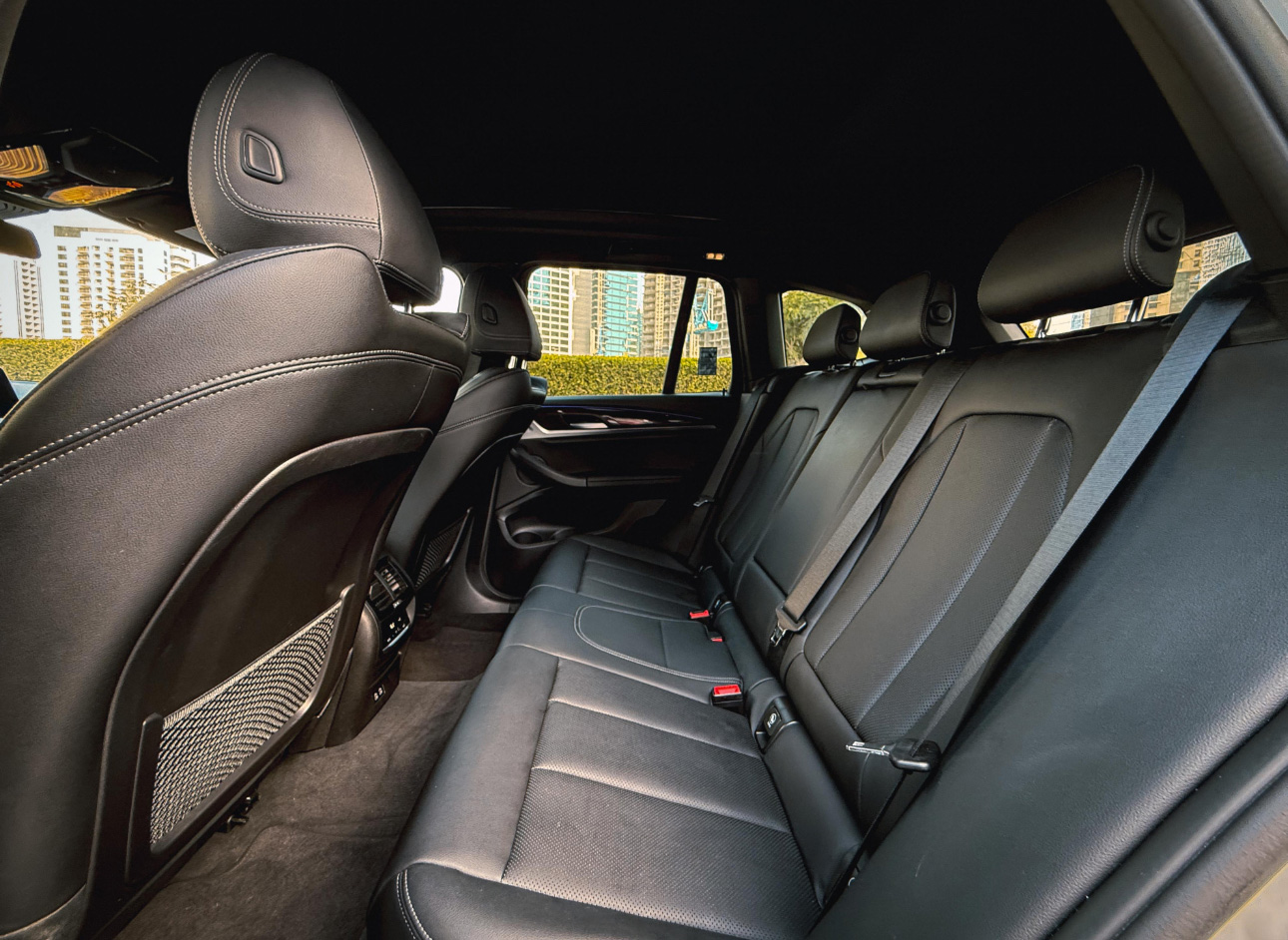 Luxury car interior with black leather seats and modern urban view