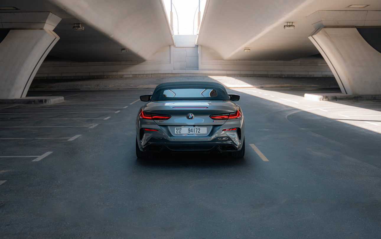 Gray BMW convertible parked in minimalist concrete parking garage