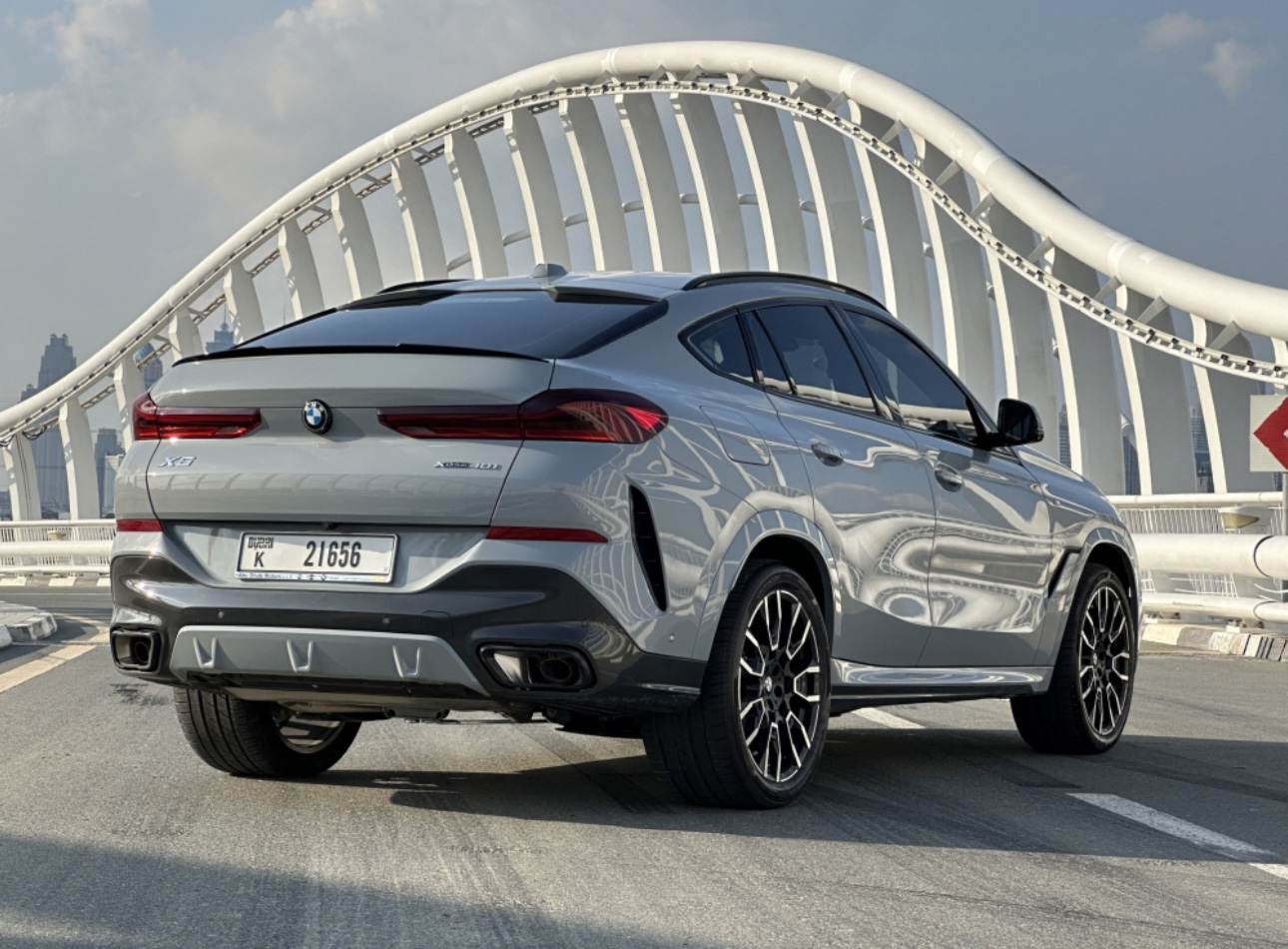 Silver BMW X6 SUV parked on bridge with modern architectural background