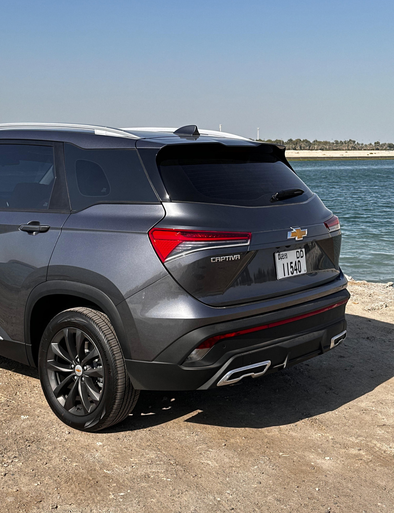 Gray Chevrolet Captiva SUV parked by the water on rocky shore