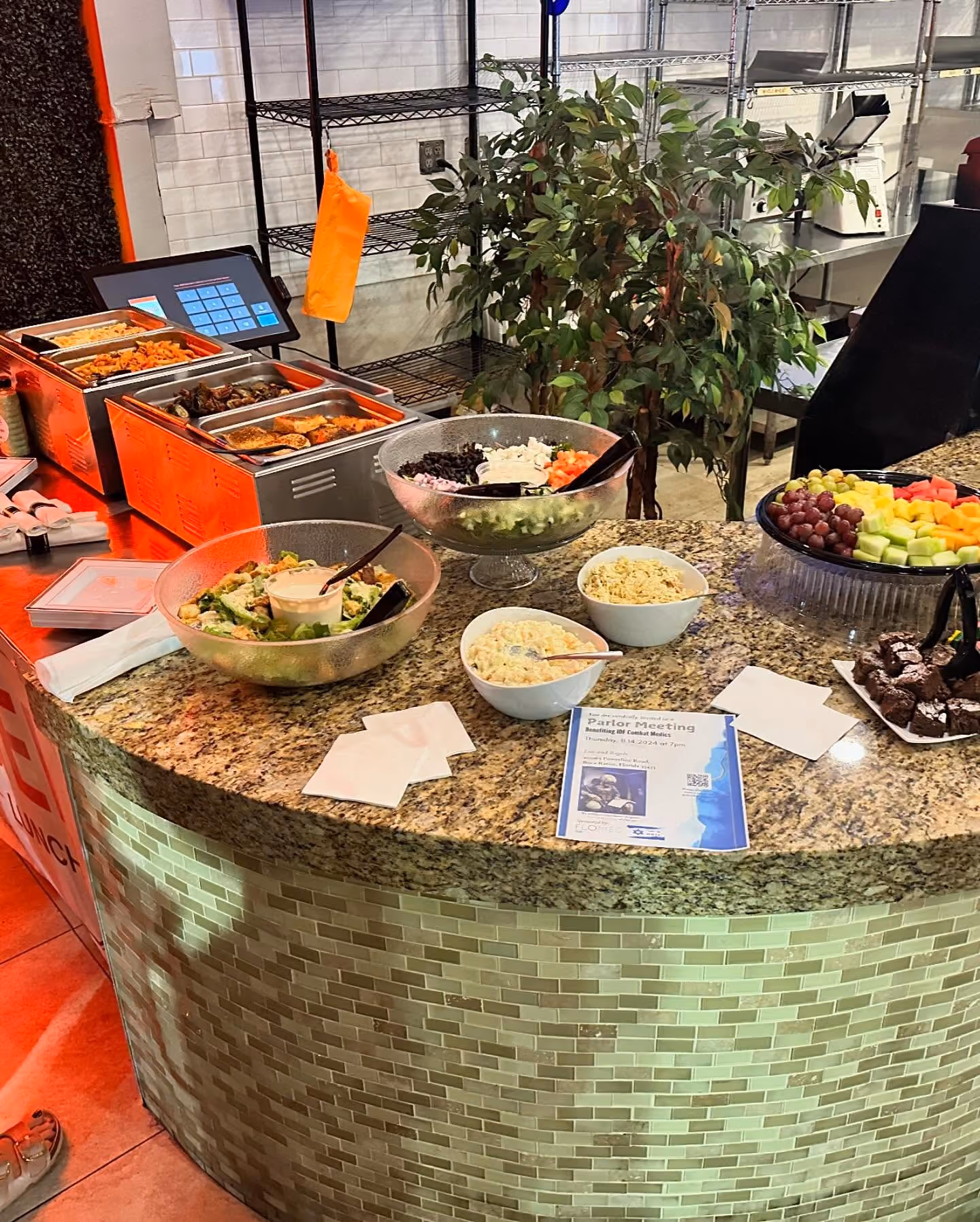 Buffet counter with salad bowls, fruit platter, desserts, and buffet trays.