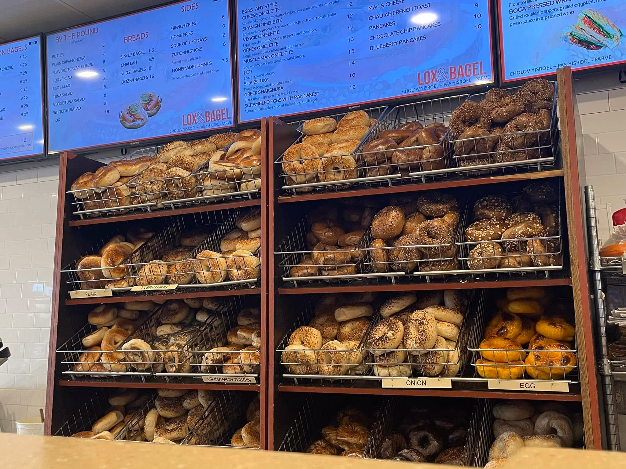 Multiple baskets filled with assorted bagels, including plain, cinnamon raisin, onion, and egg varieties.