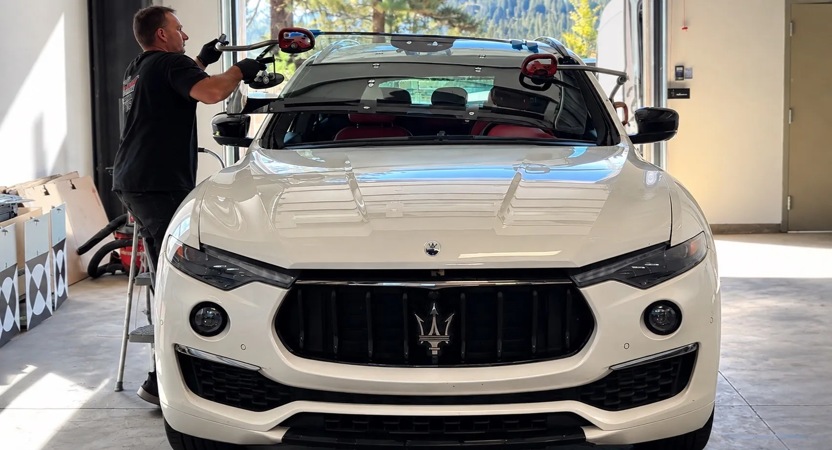 Technician installing a windshield on a white Maserati at Sierra Mobile Auto Glass & Calibration in Truckee