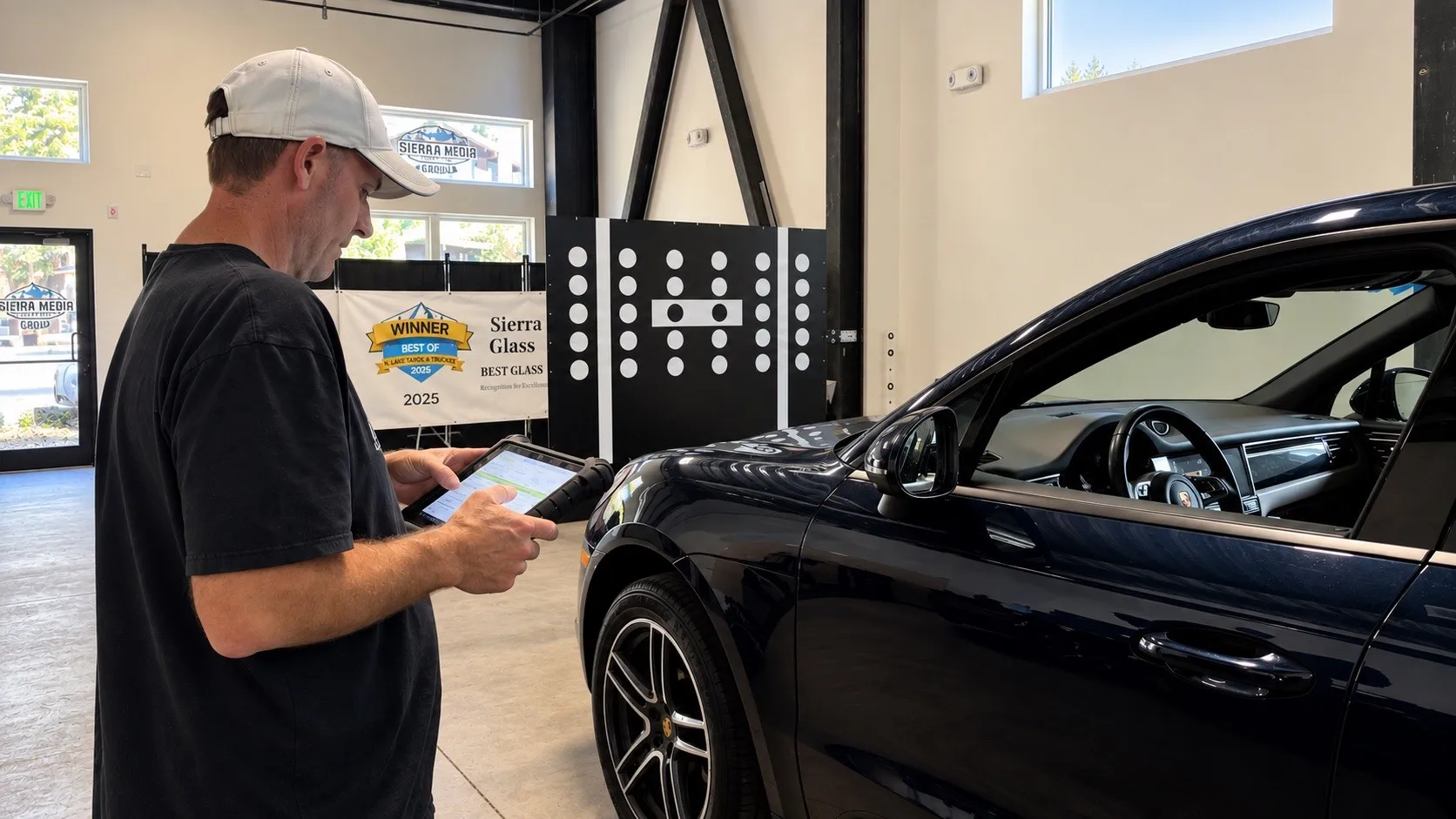 Technician using a diagnostic tablet beside a Porsche with ADAS calibration targets at the Truckee shop.