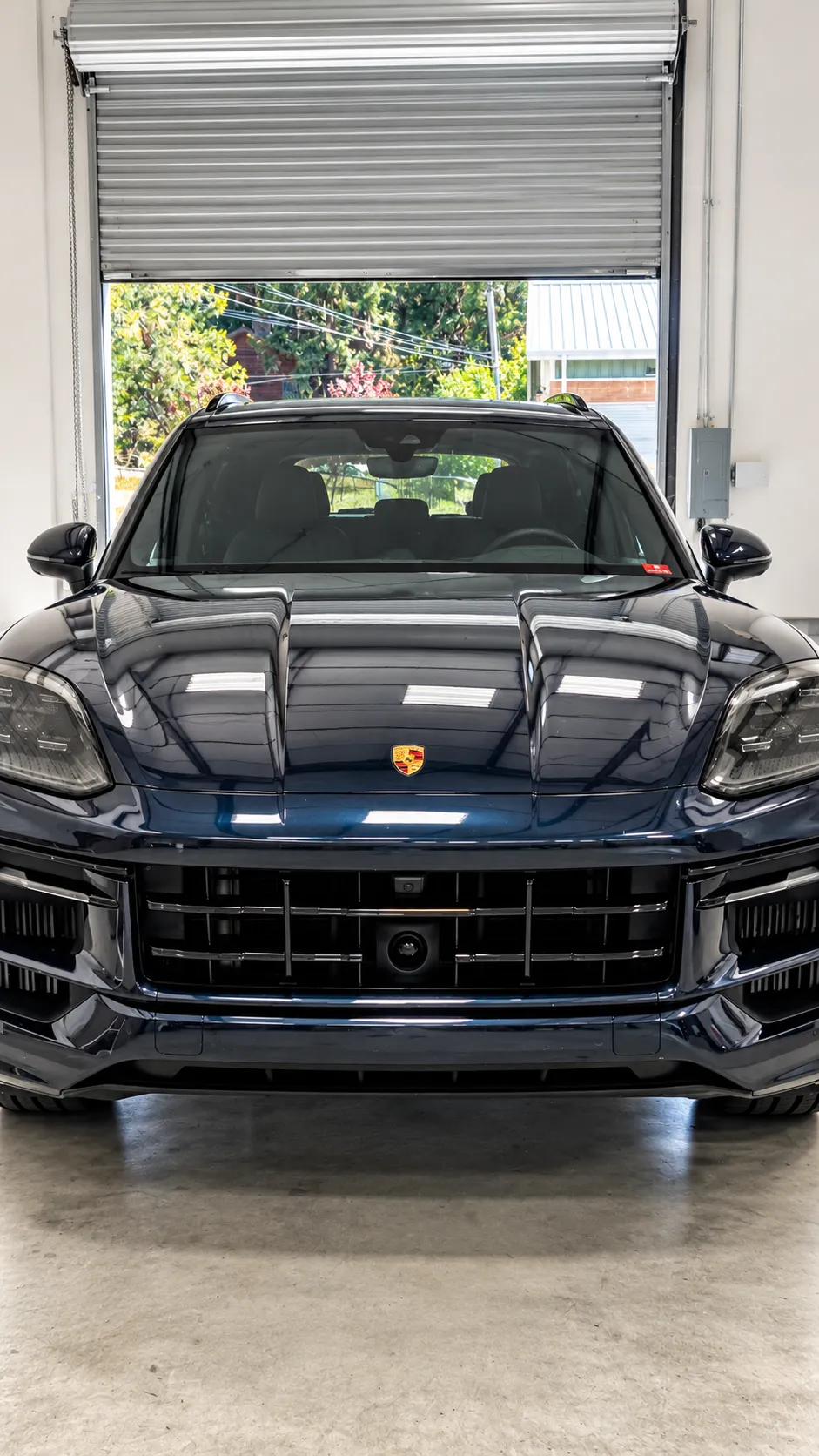 Front view of a dark Porsche SUV inside the Truckee service bay.