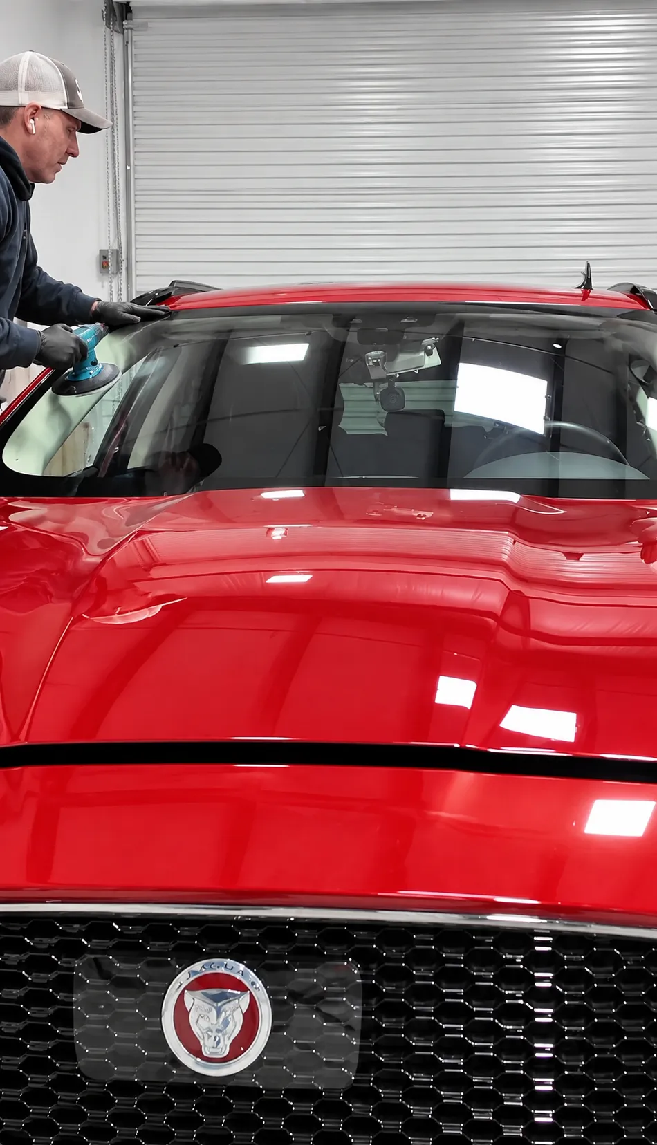 Technician working at the windshield of a red Jaguar SUV in the Truckee shop.