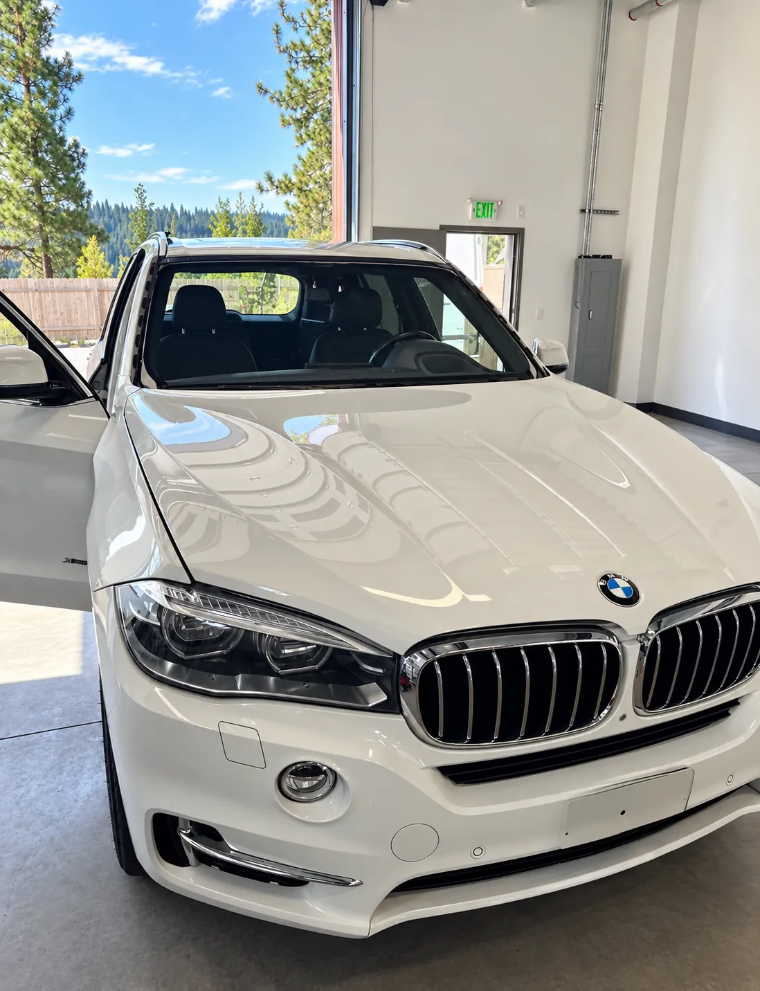 White BMW SUV with an open door in the Truckee service bay.