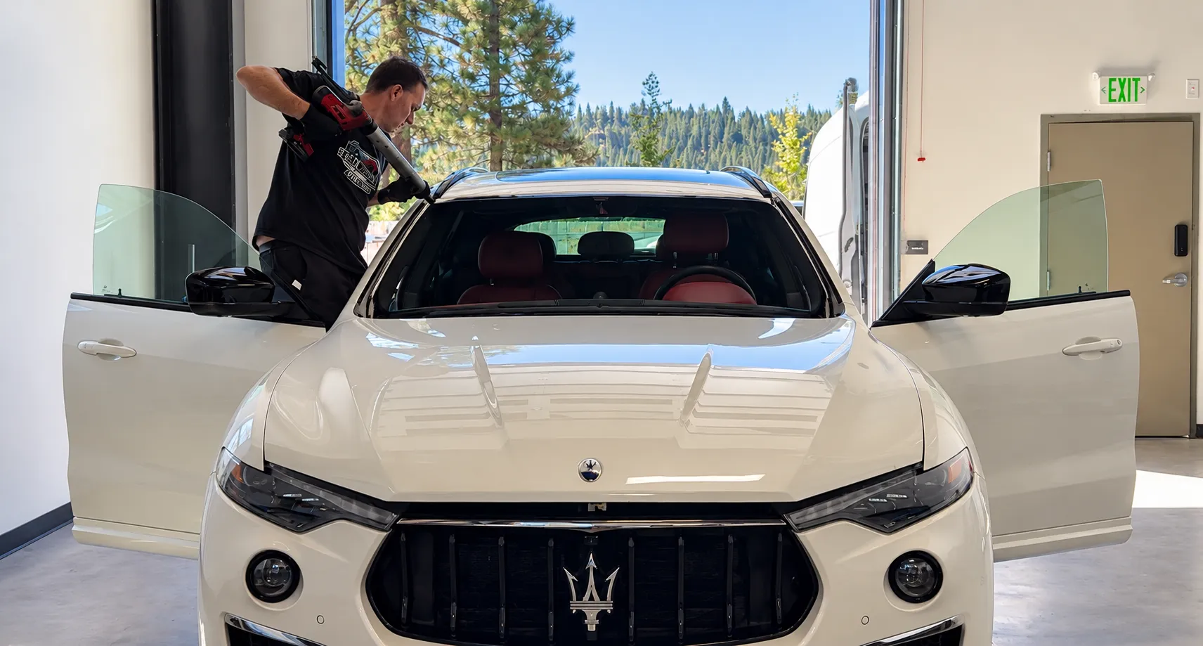 Technician working at the windshield of a white Maserati SUV in the Truckee shop.