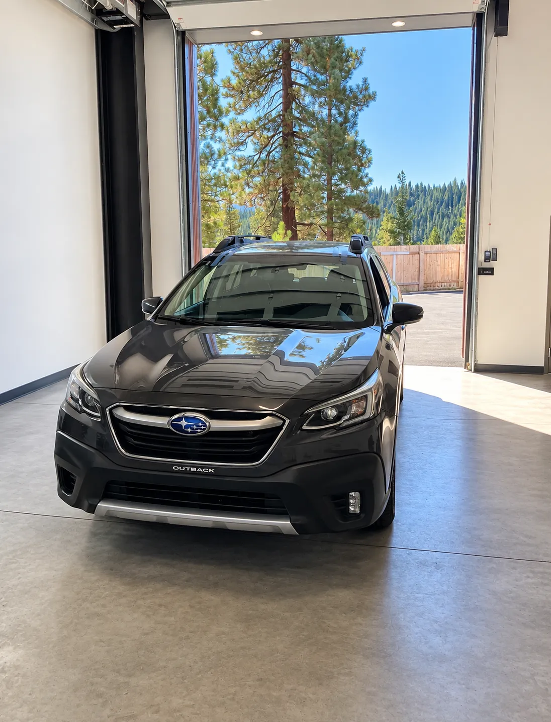 Dark Subaru Outback facing the open service-bay door at the Truckee shop.