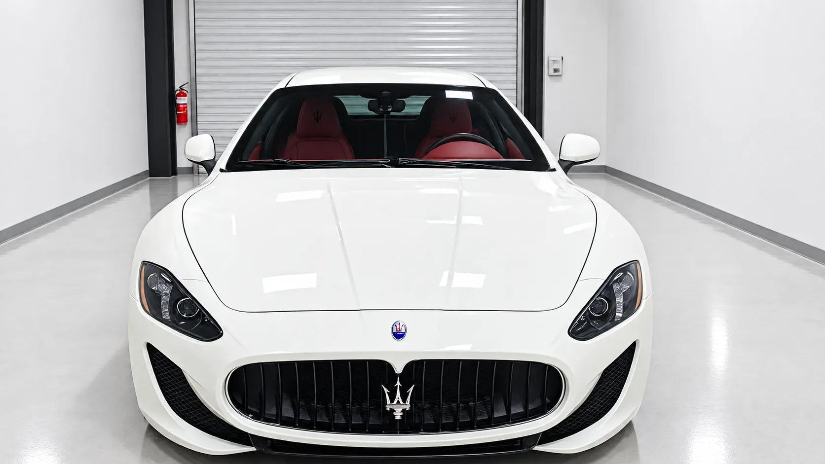 Front view of a white Maserati coupe with a red interior in the Truckee shop.